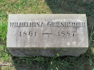 A grave marker in the grass on a sunny day