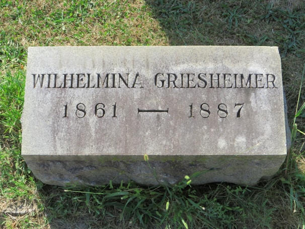 A grave marker in the grass on a sunny day