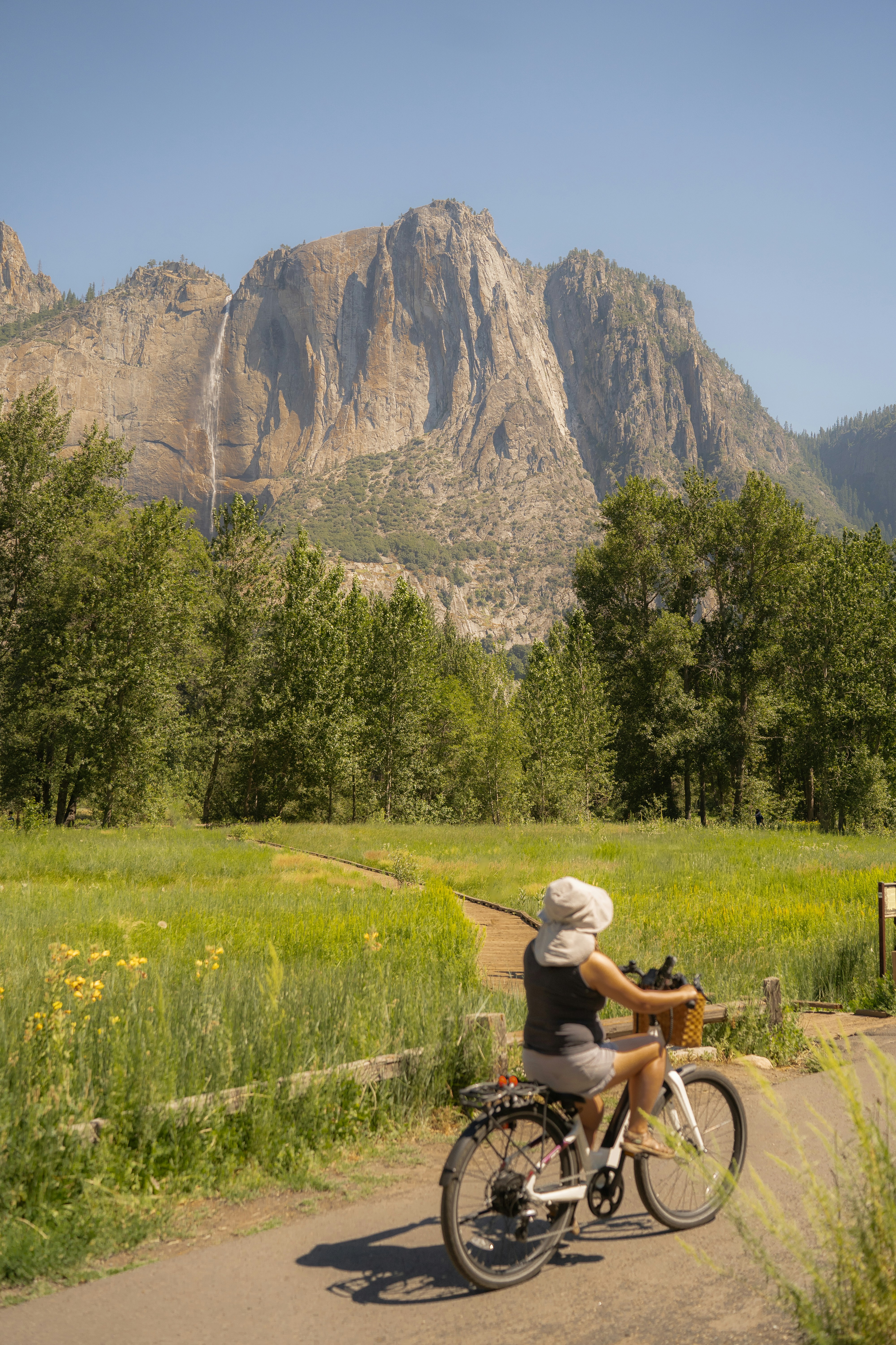 A woman riding a bike down a dirt road
