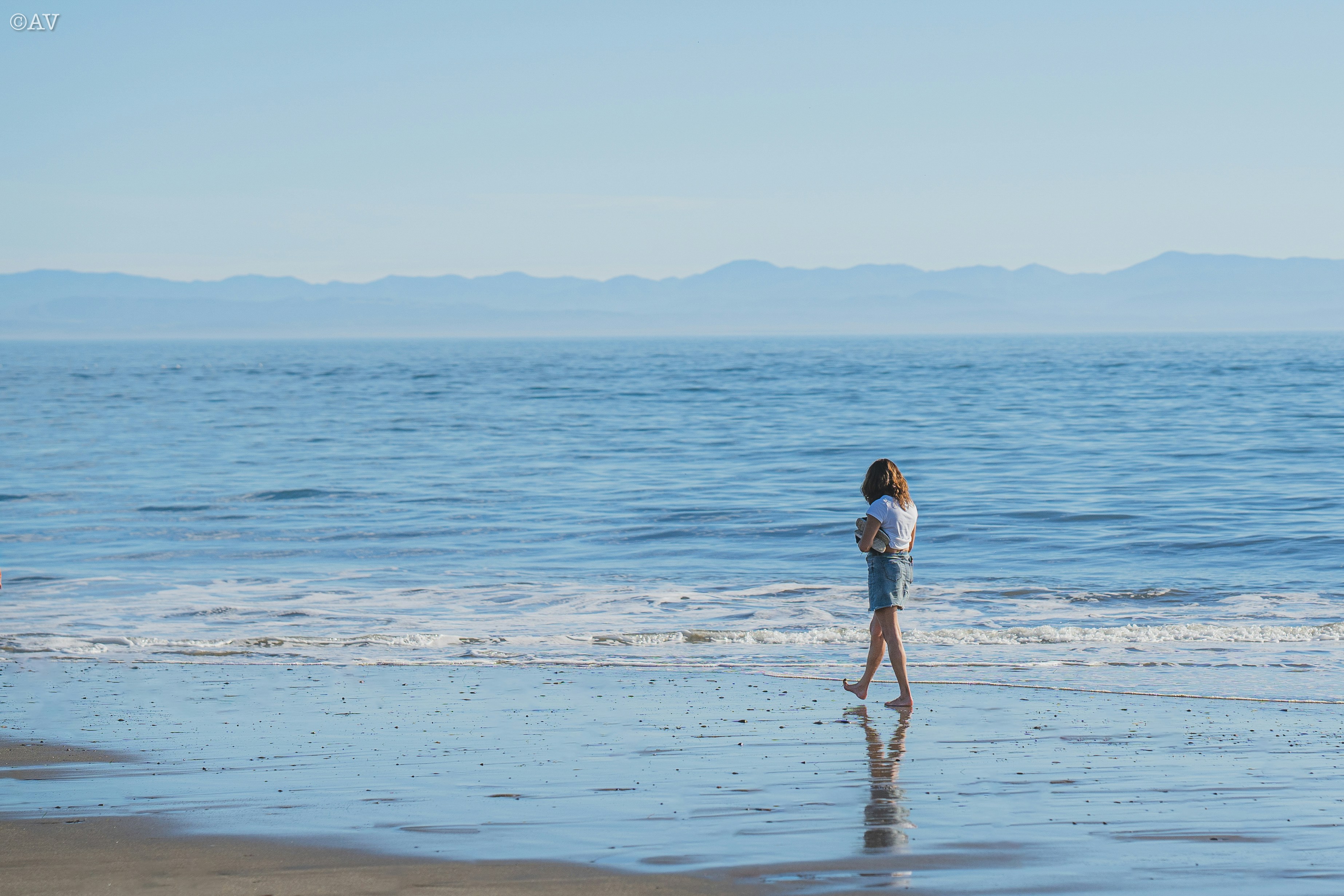 A woman standing on a beach next to the ocean