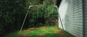 A swing set in a yard next to a house