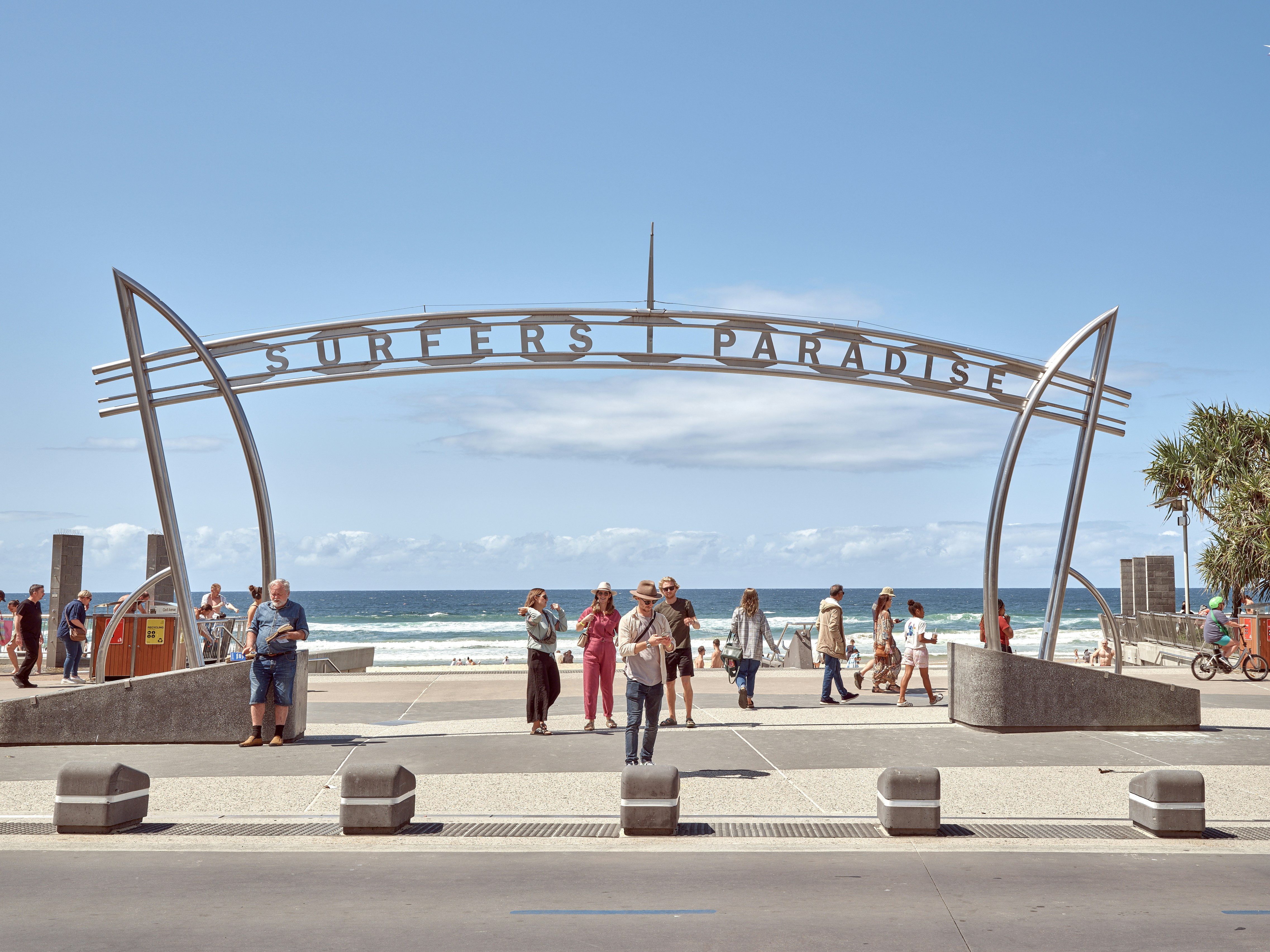 A group of people walking down a sidewalk next to the ocean