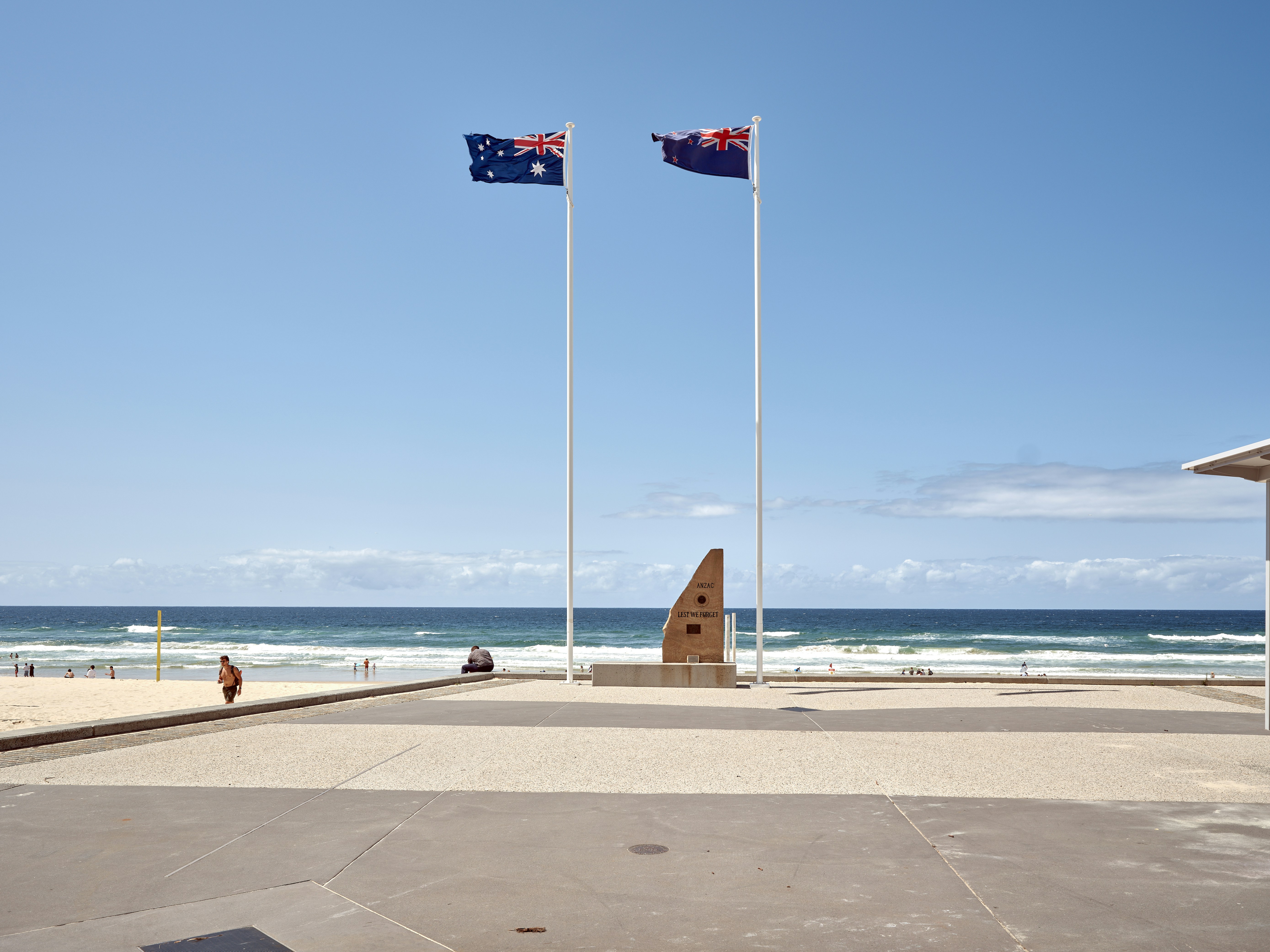 Two flags flying in the wind on a beach