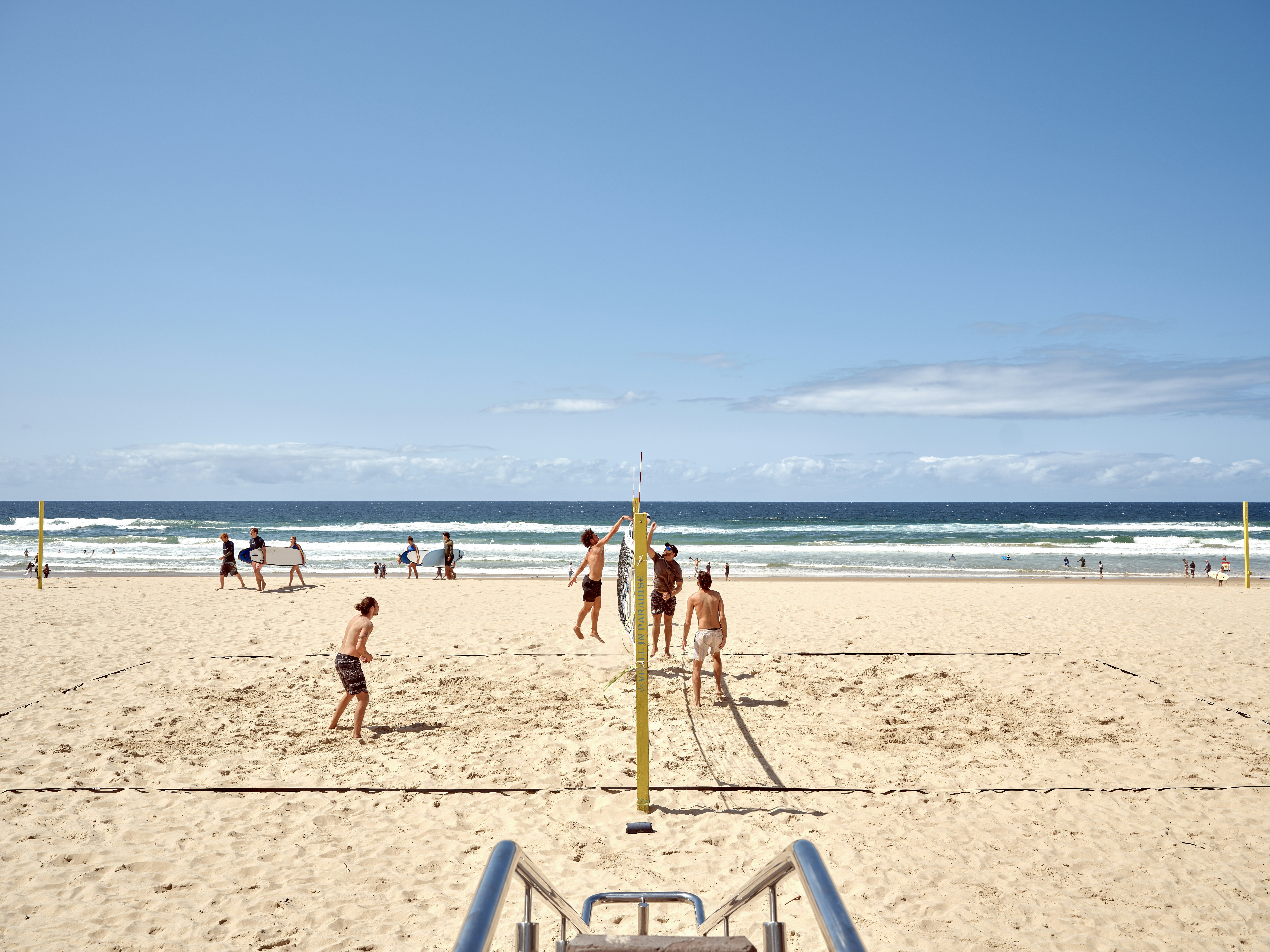 A group of people playing volleyball on a beach