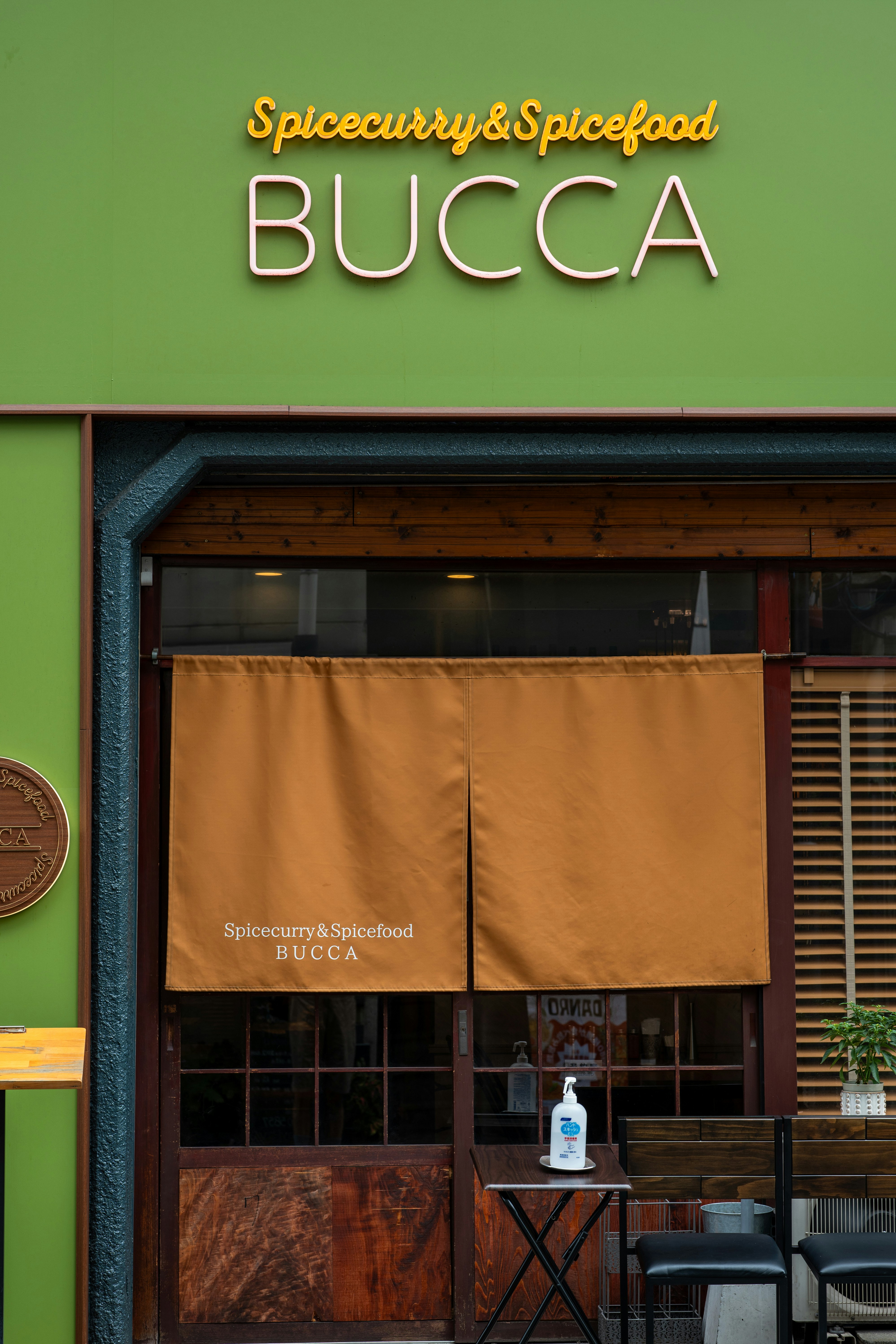 A green building with a sign that says bucca