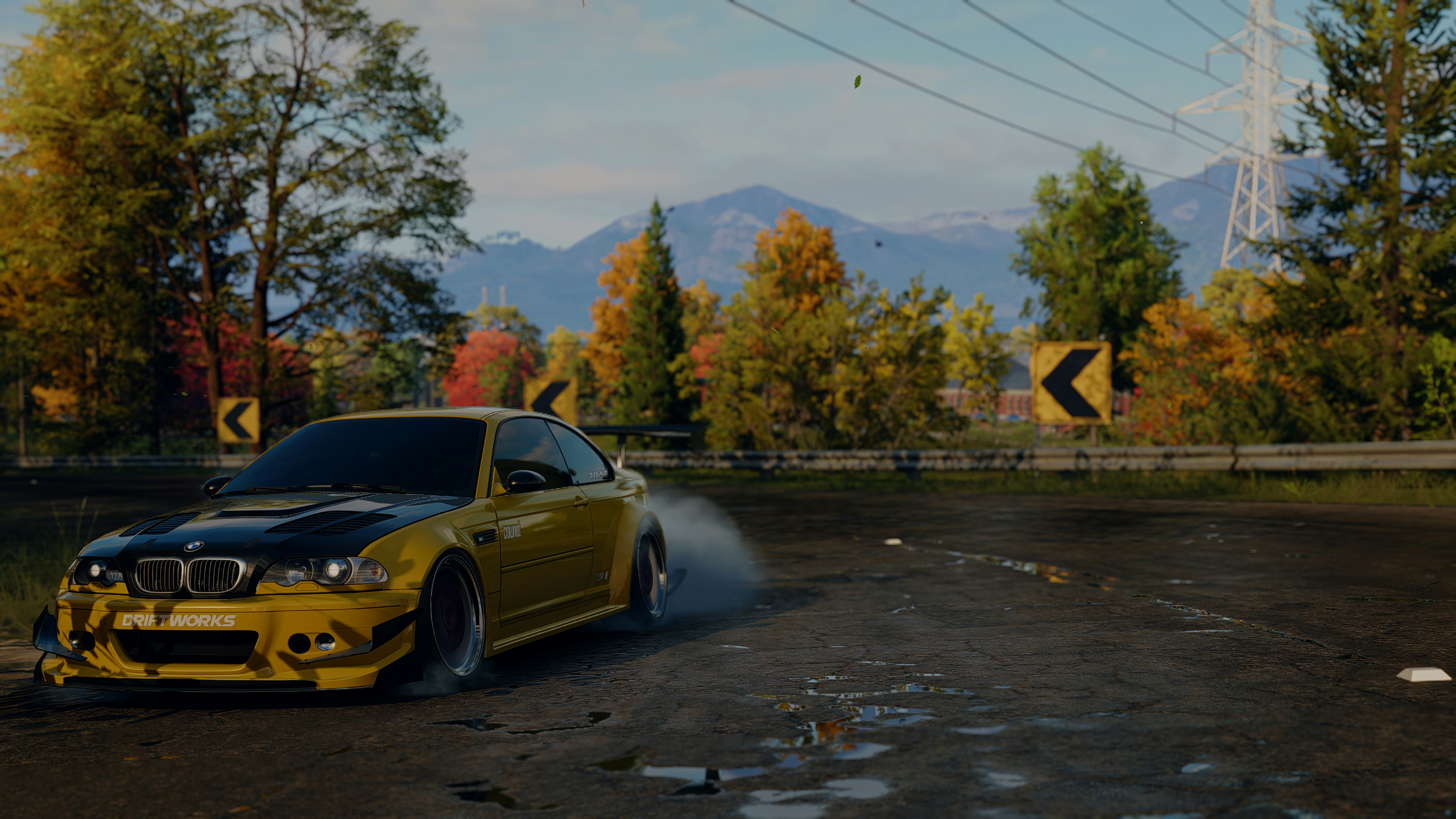 A yellow car driving down a road next to a forest