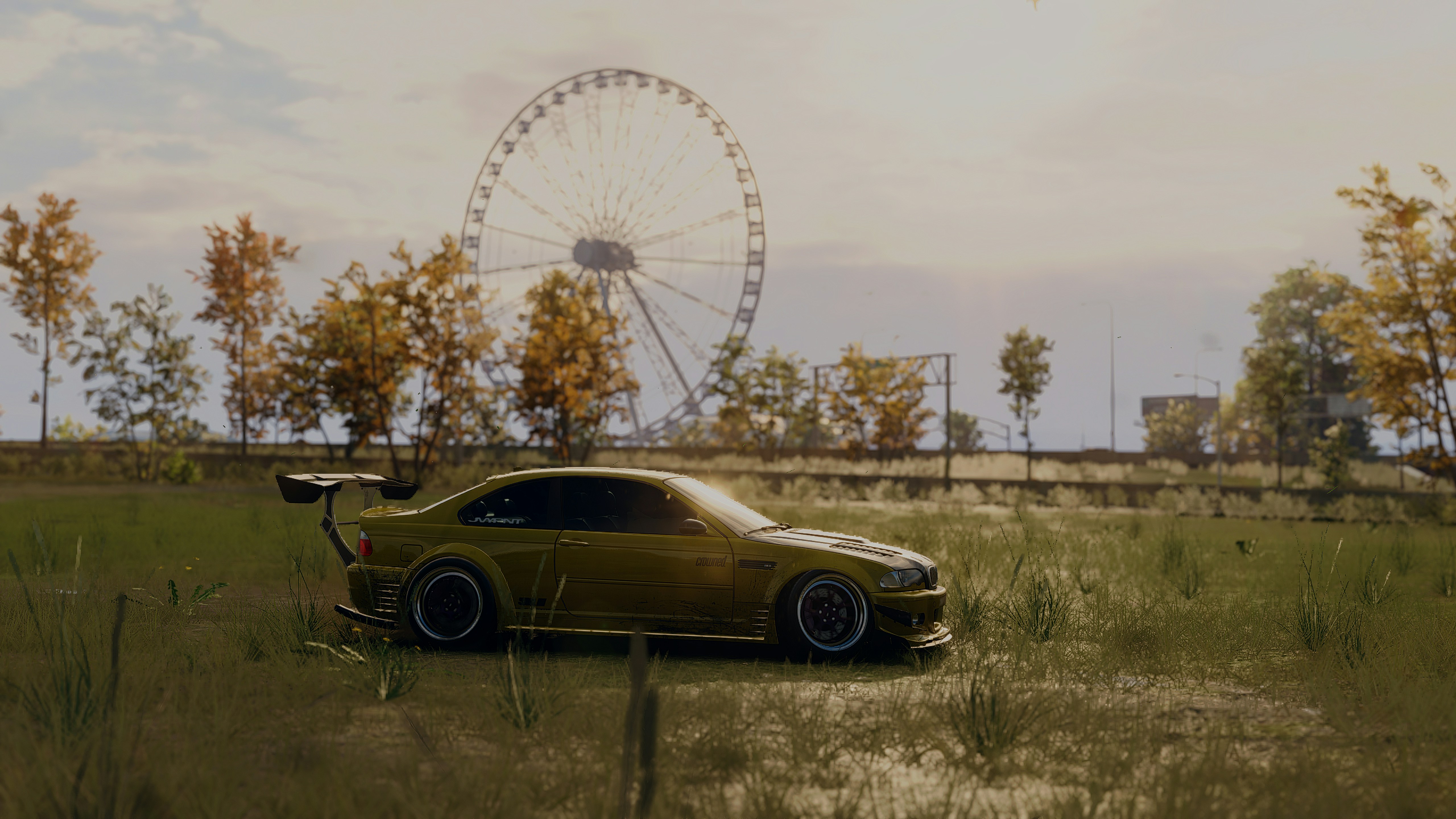 A car parked in a field with a ferris wheel in the background