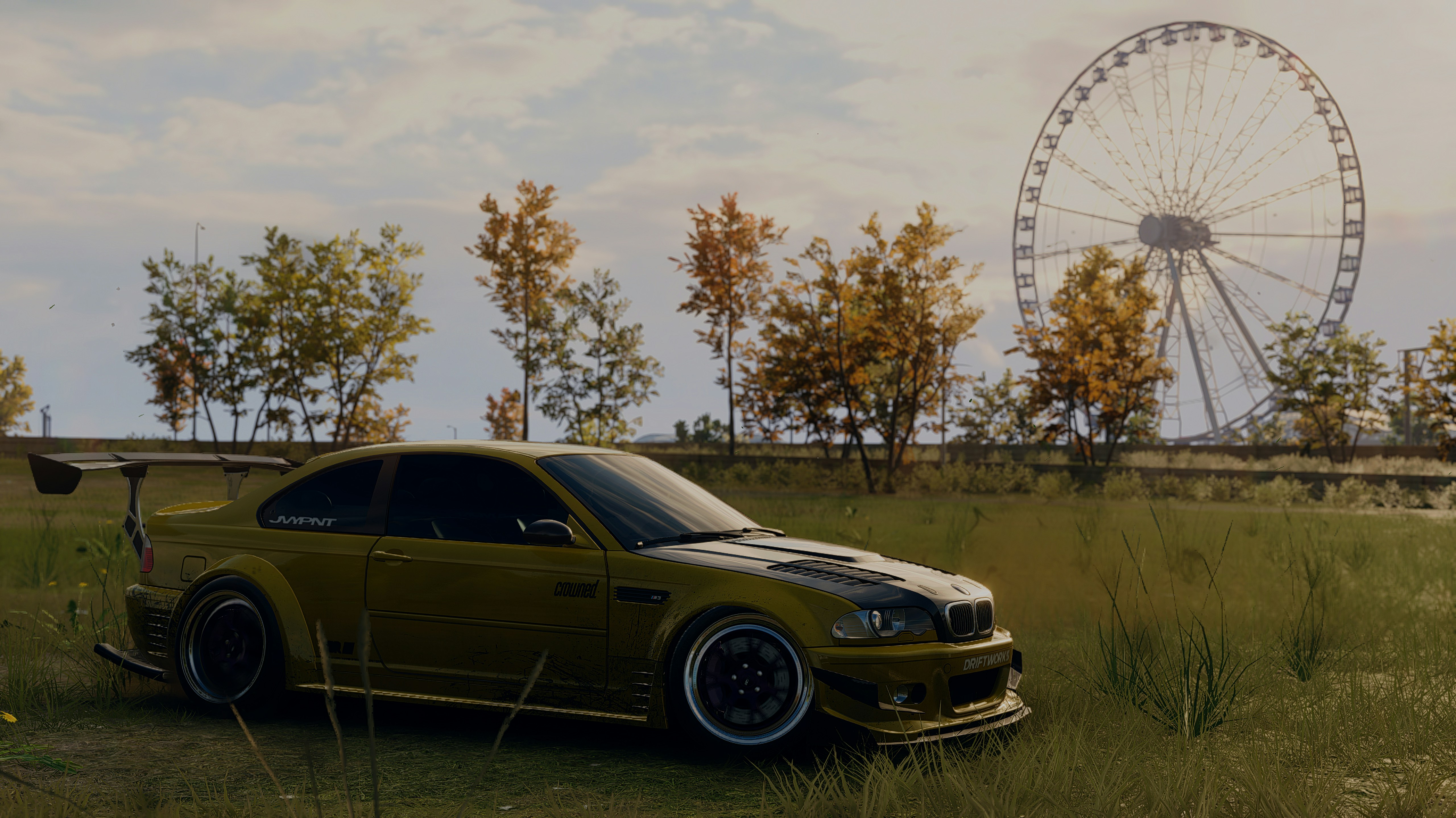 A car parked in a field with a ferris wheel in the background