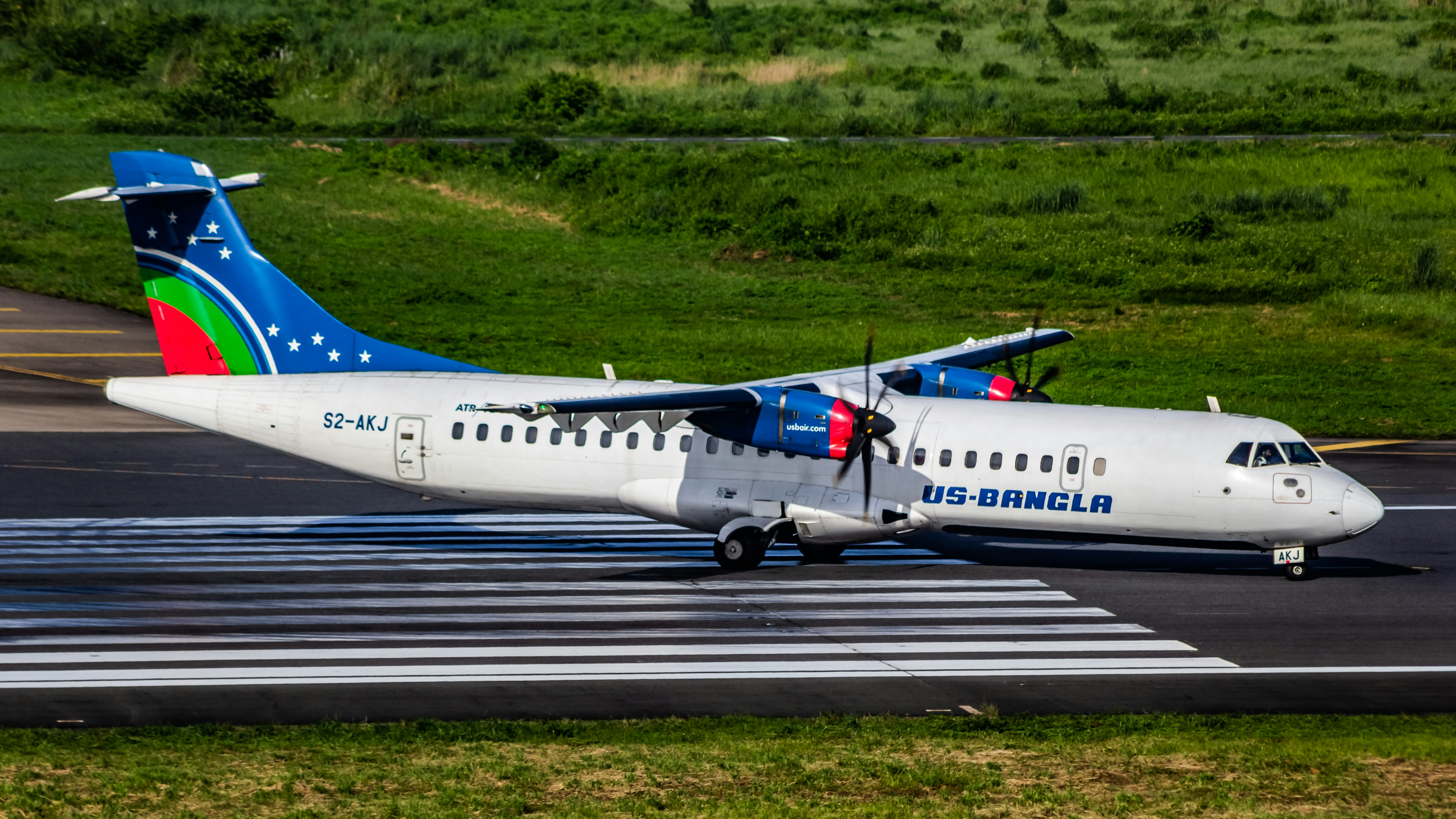 A large passenger jet sitting on top of an airport runway, US-Bangla Airlines | ATR 72-600 | S2-AKJ