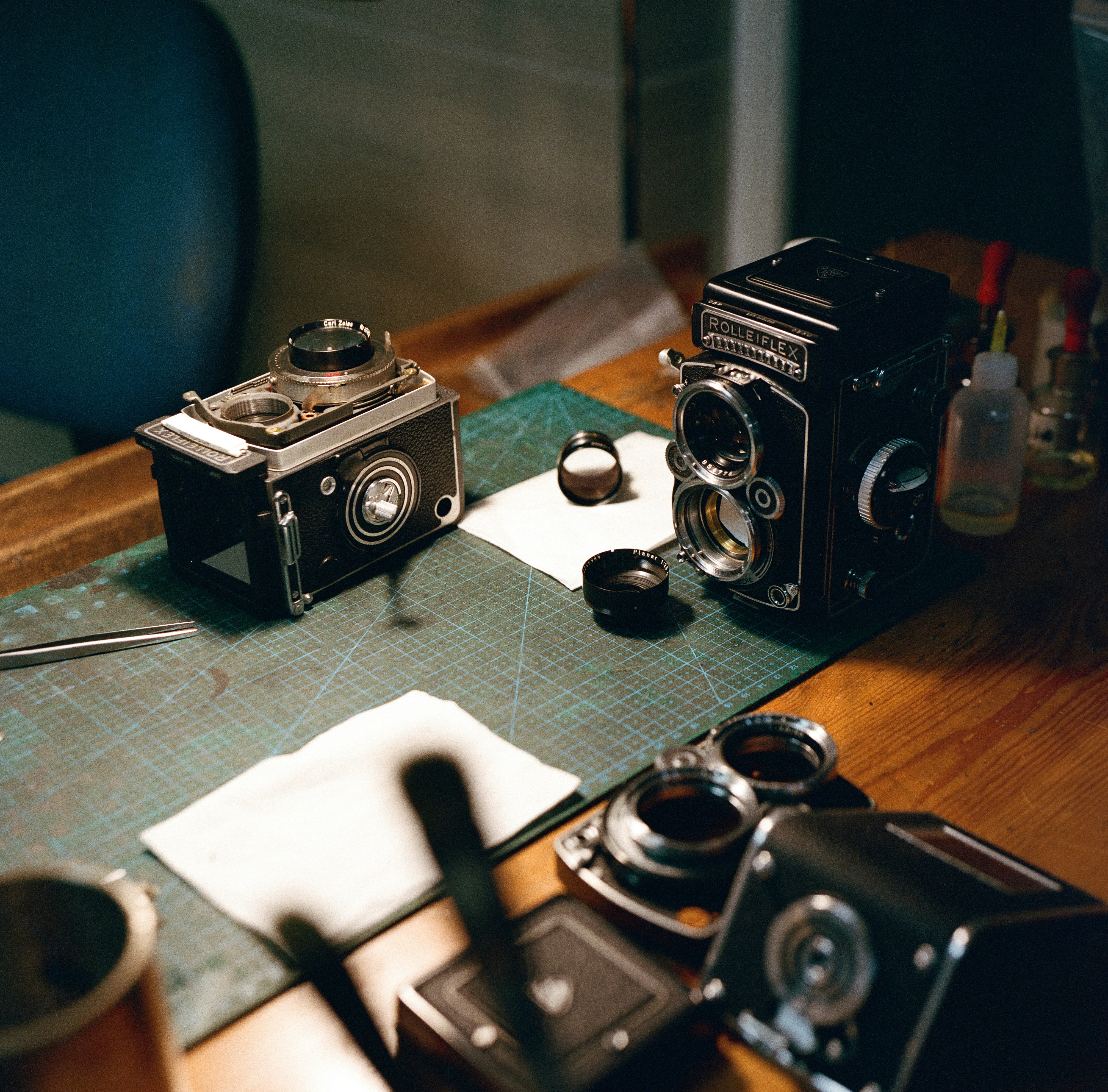 Two old cameras sitting on a table next to a cup of coffee