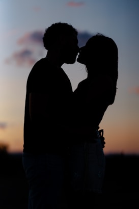 A silhouette of a couple kissing in front of a sunset