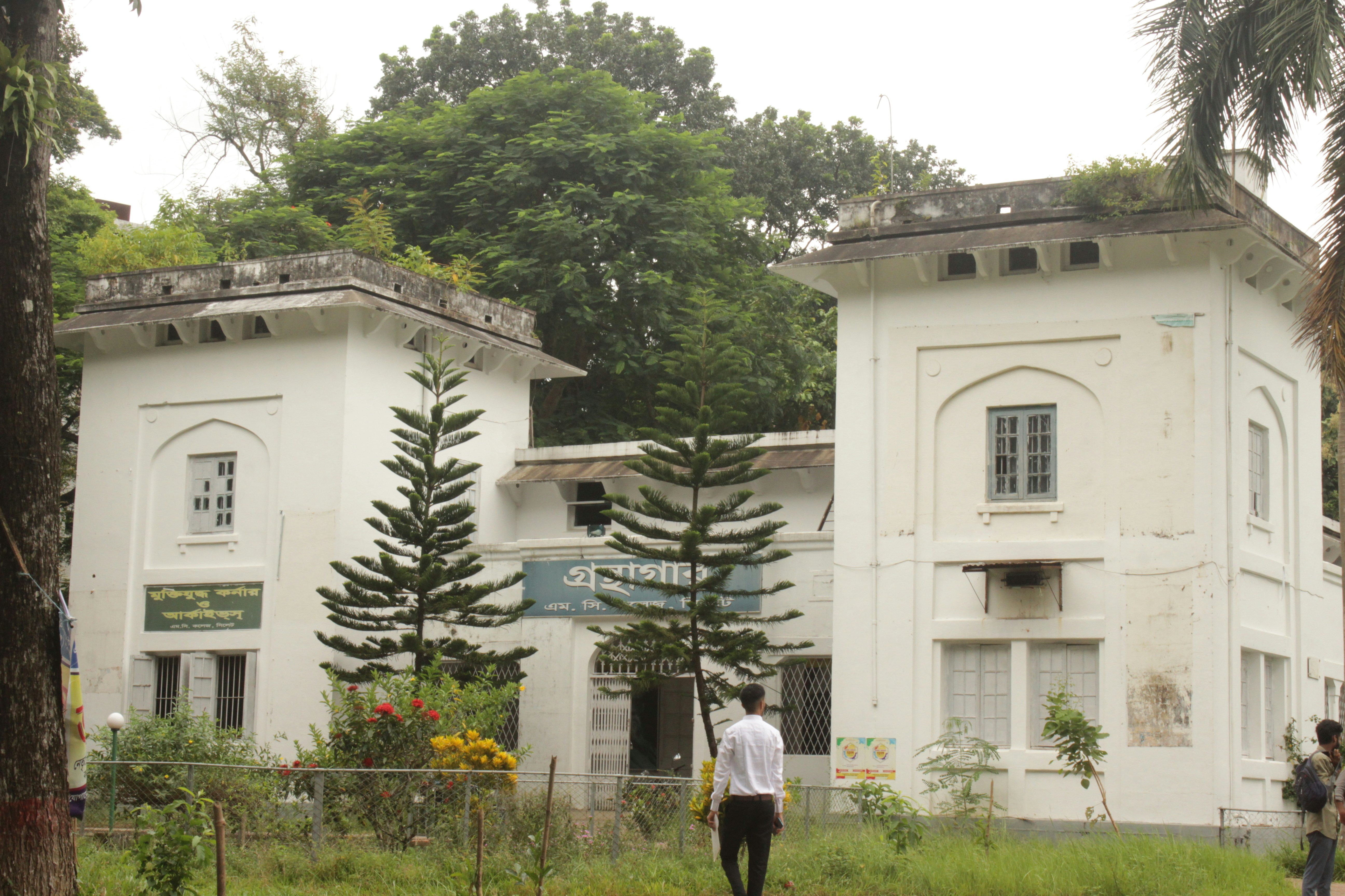 A man standing in front of a large white building