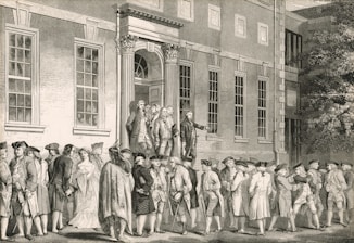 Men gather outside a grand building with classical architecture.