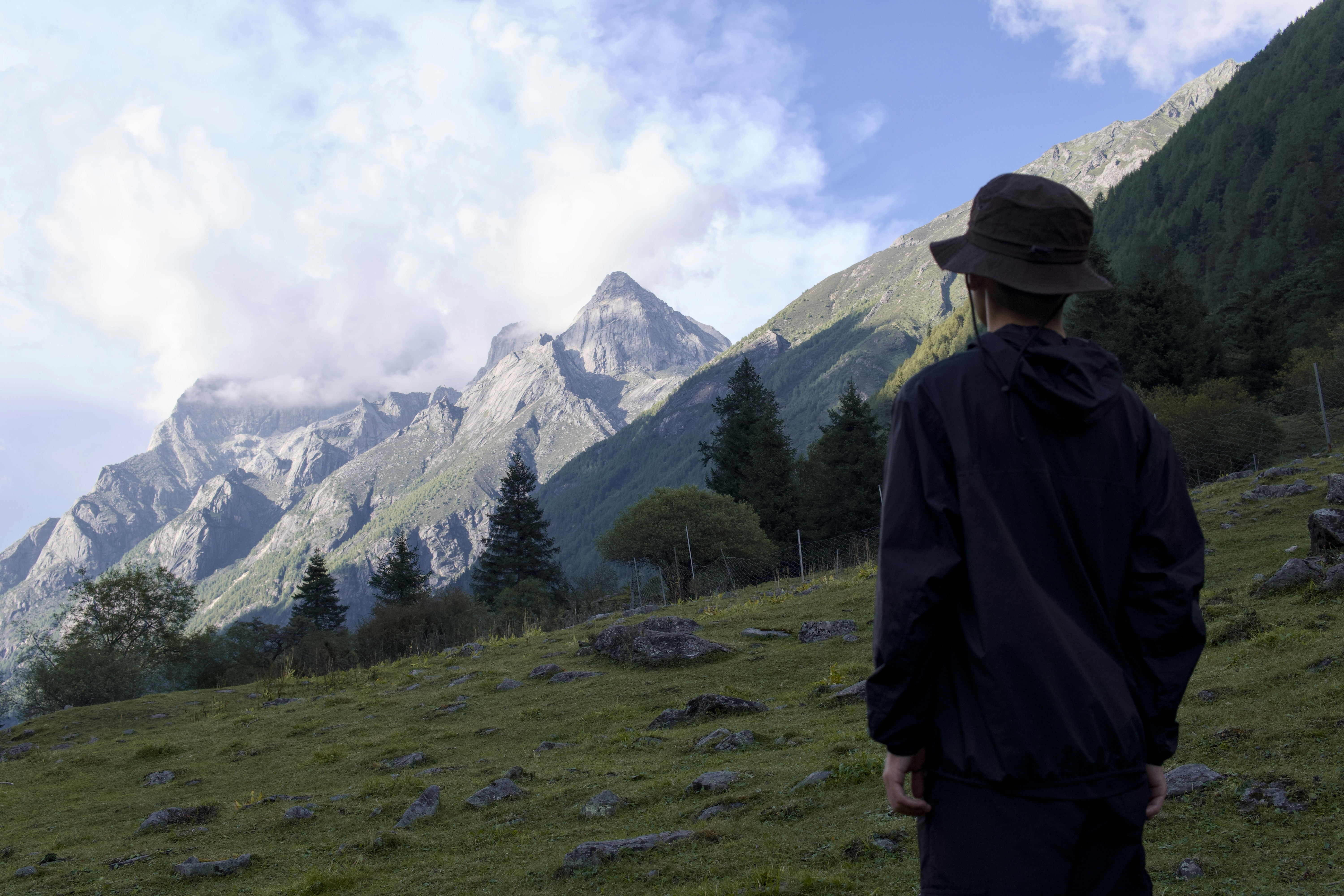 Un hombre de pie en la cima de una exuberante ladera verde
