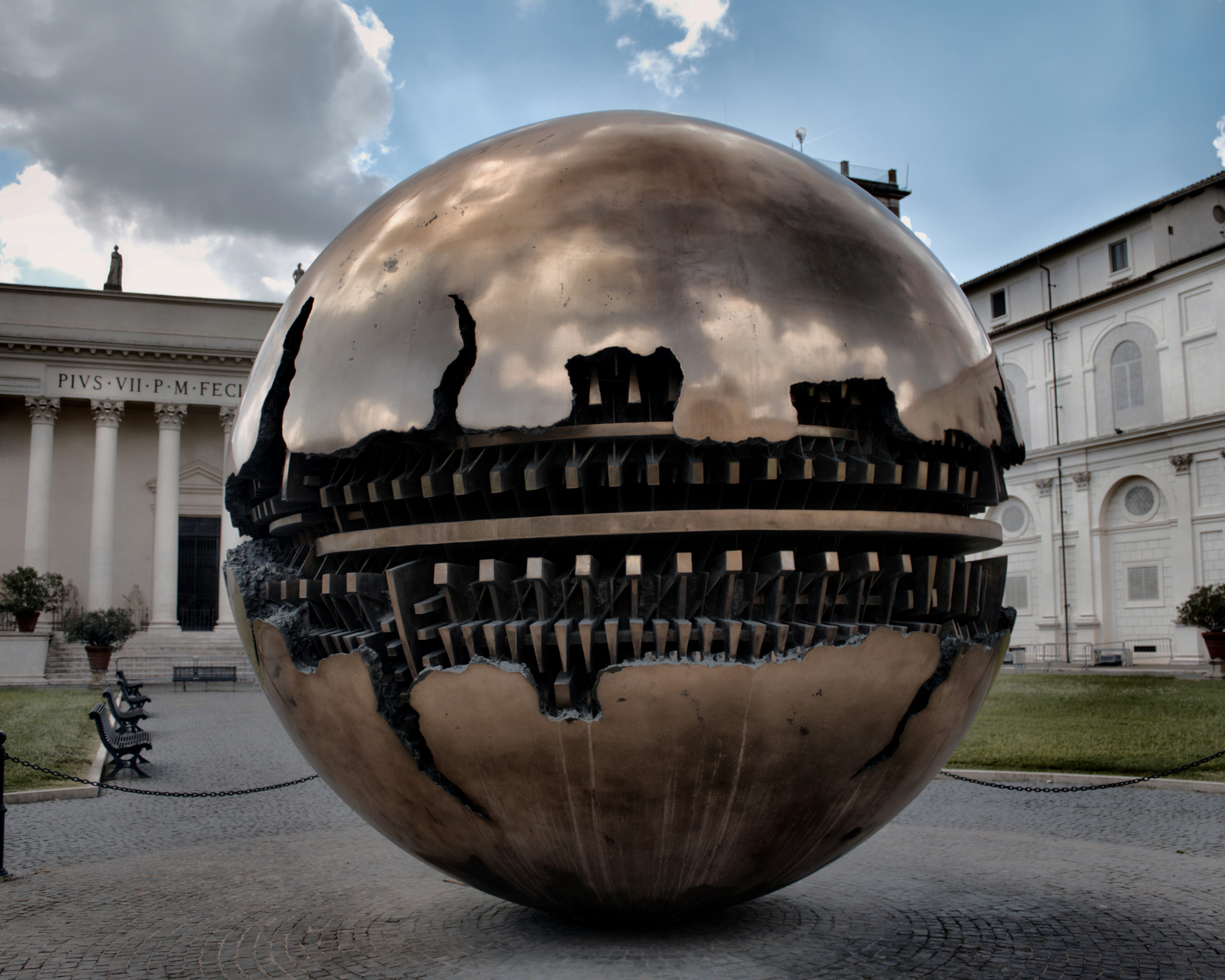 A large metal ball sitting in front of a building