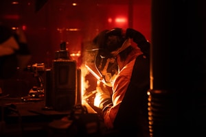 A man is welding in a dark room