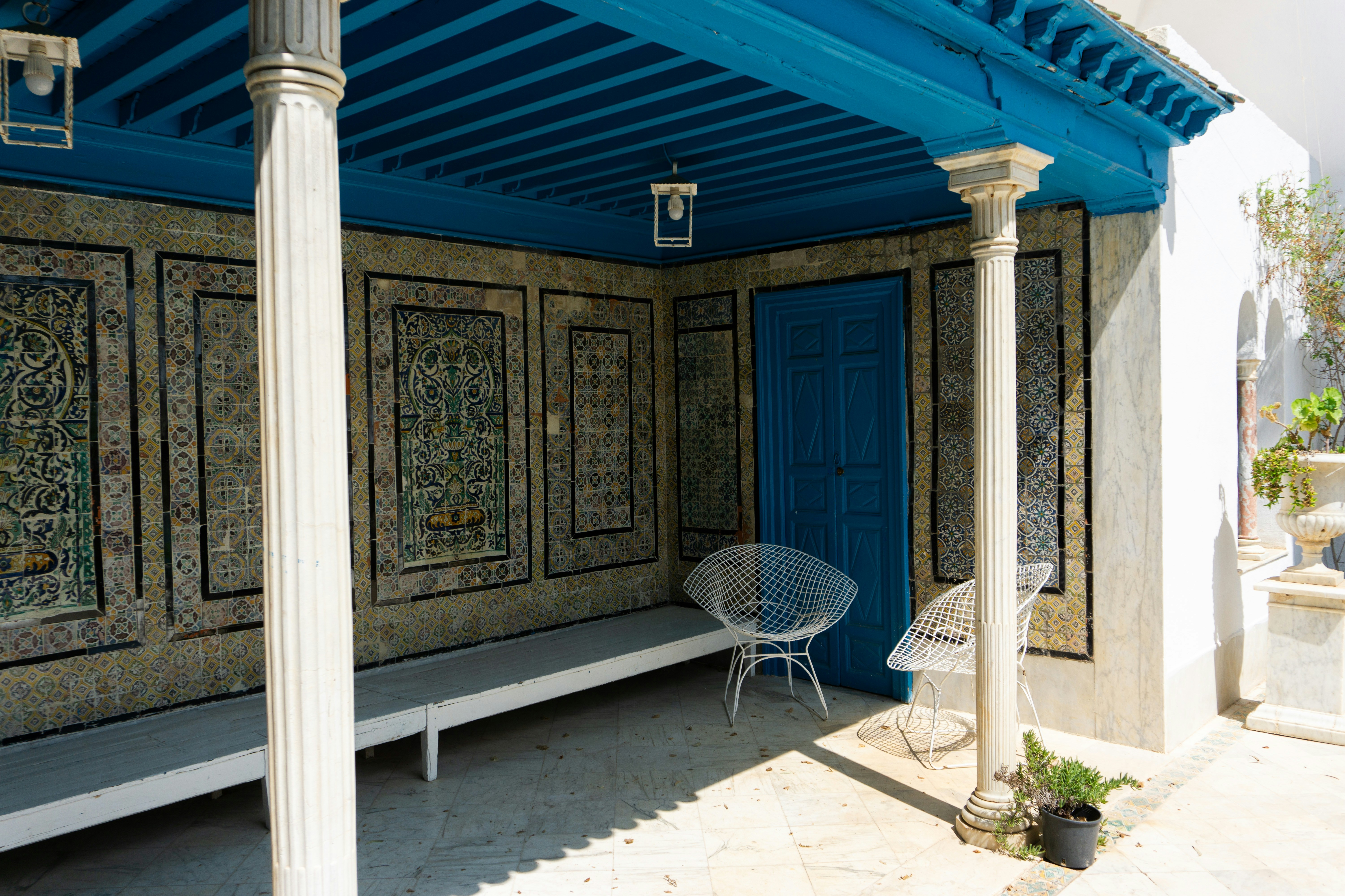 A porch with a blue awning and a white chair