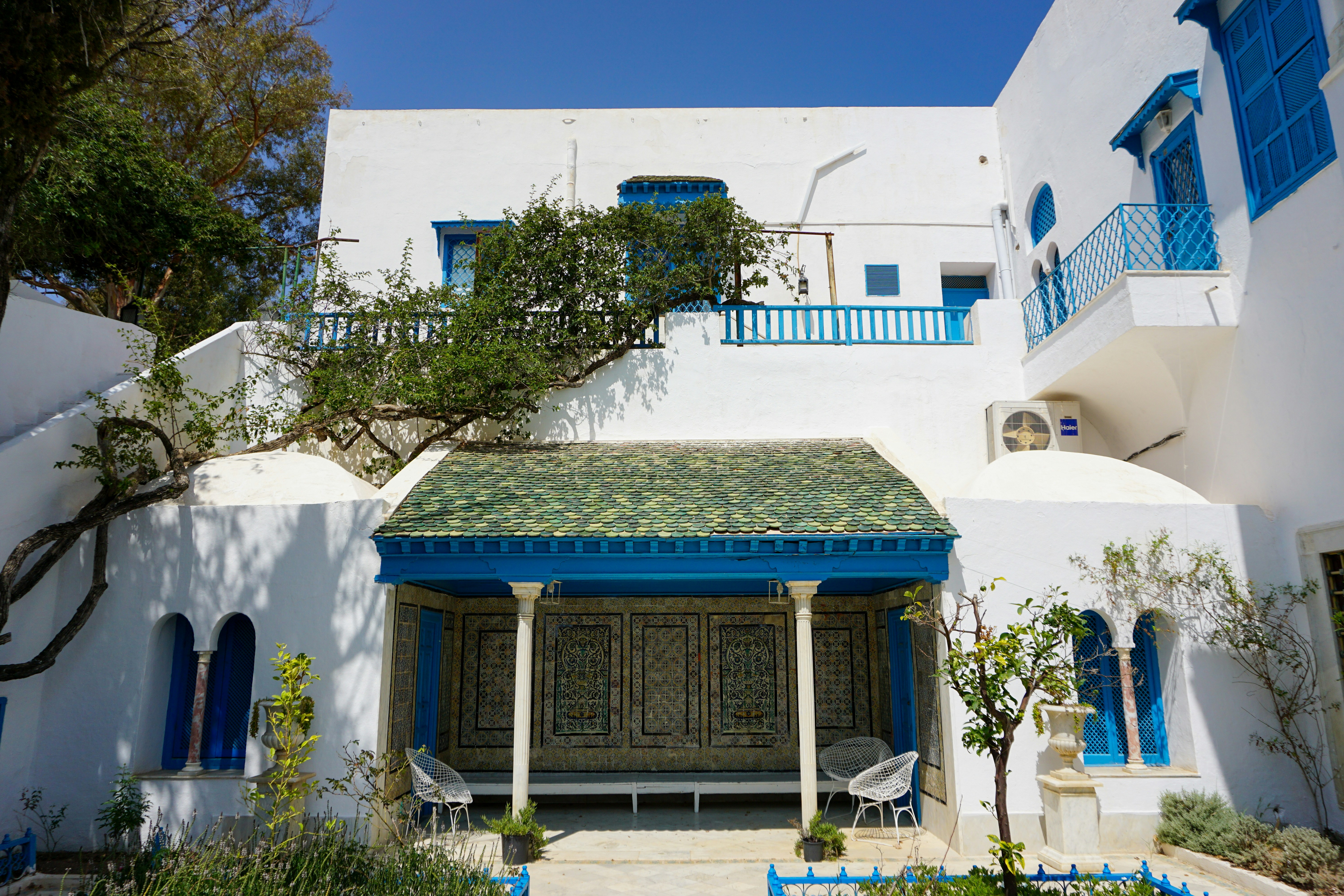A white house with blue shutters and a green roof