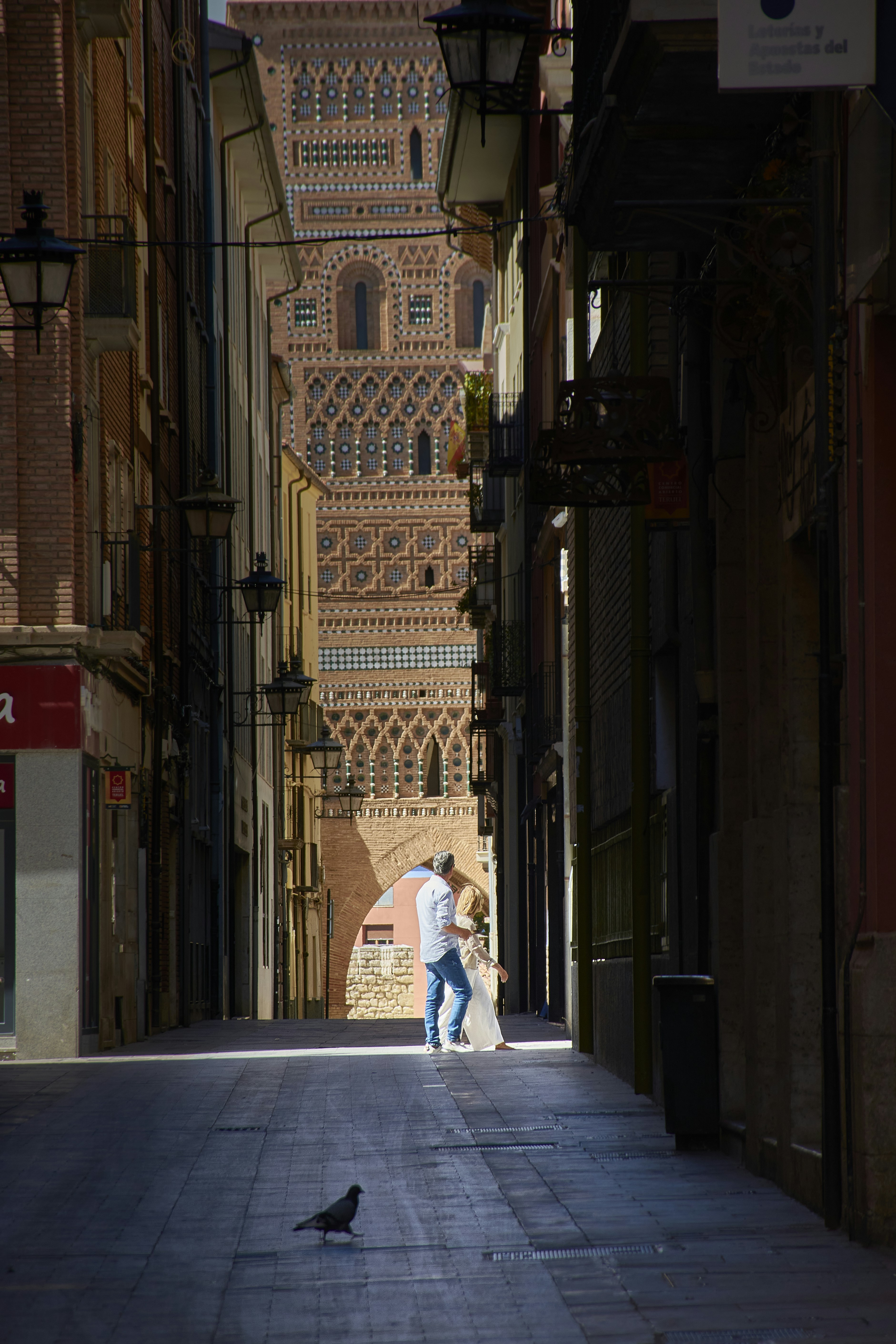 A man walking down a street next to tall buildings