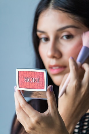 A woman holding a small container of lipstick