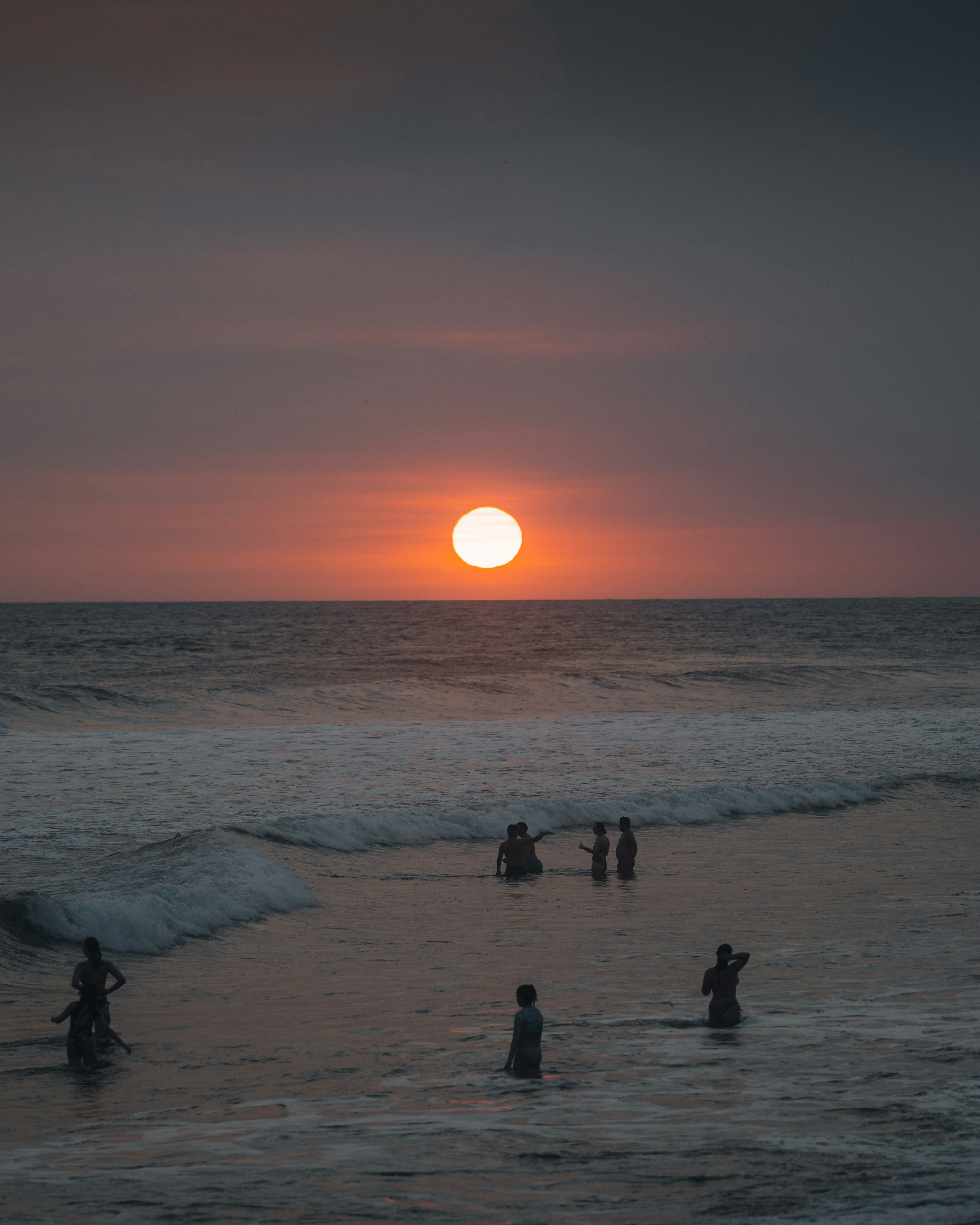 A group of people standing on top of a beach near the ocean