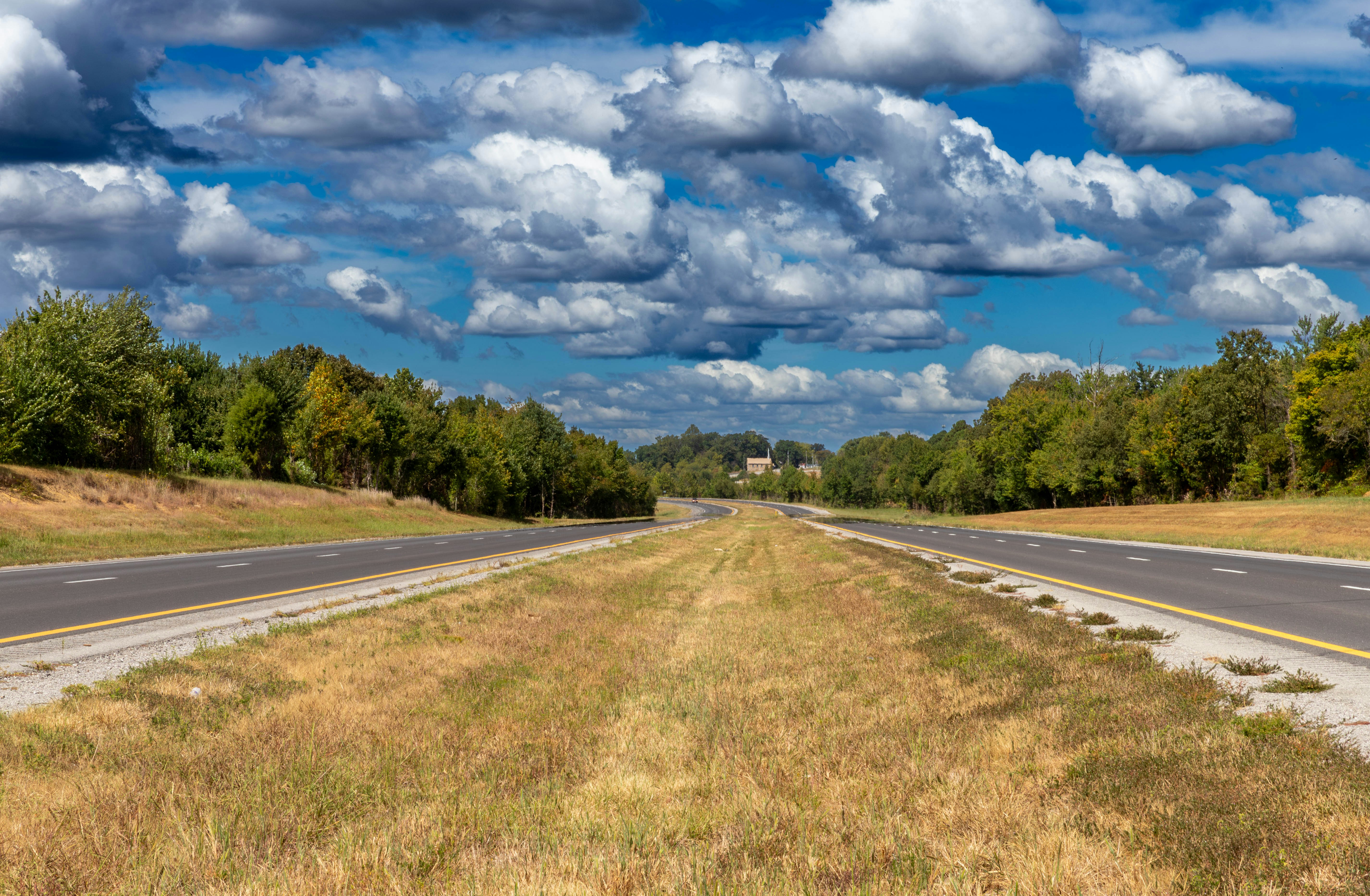 An empty road with a sky filled with clouds