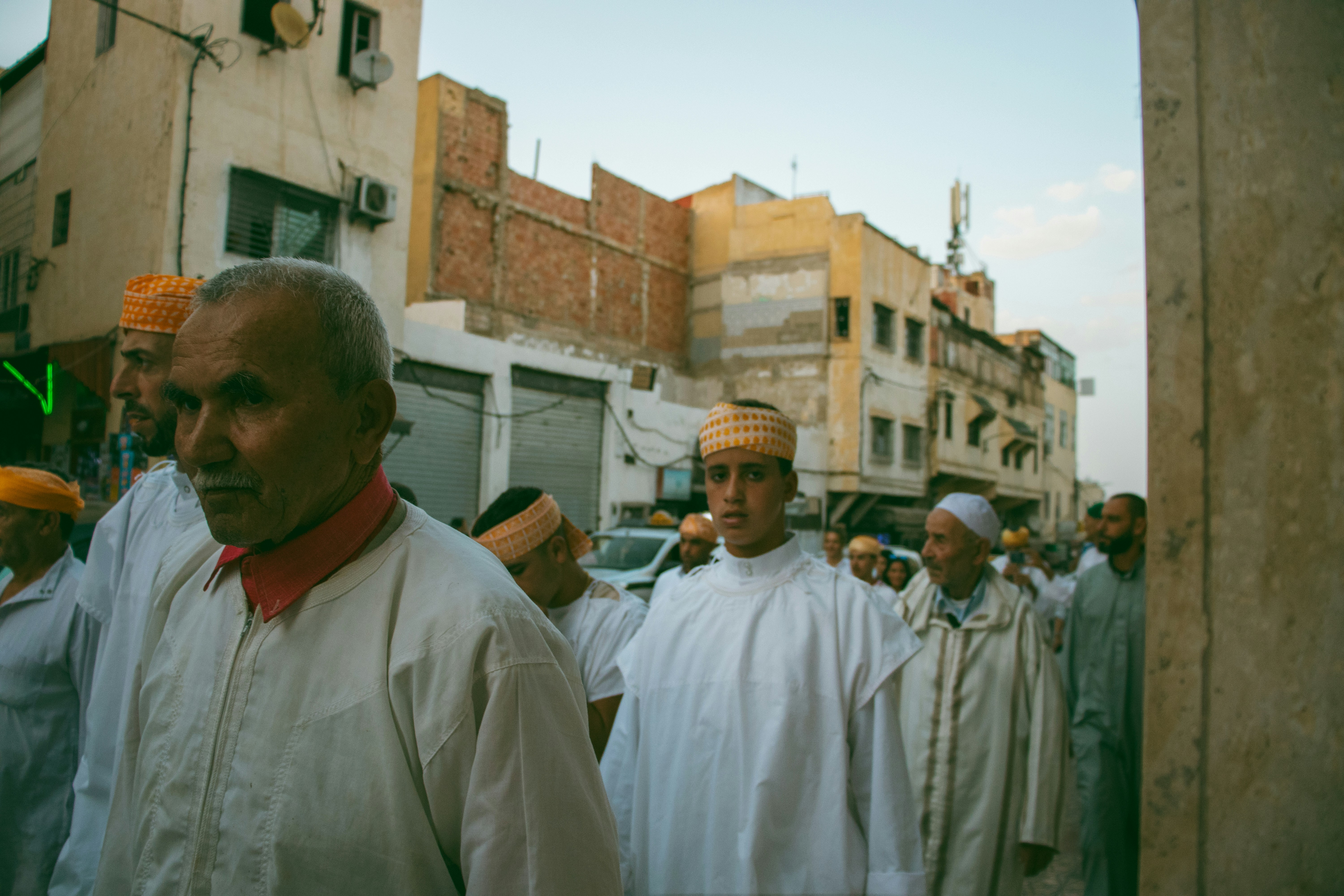 A group of men walking down a street next to tall buildings
