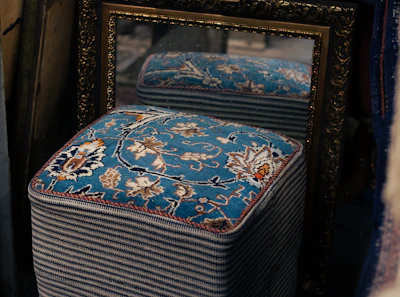 A blue ottoman sitting in front of a mirror