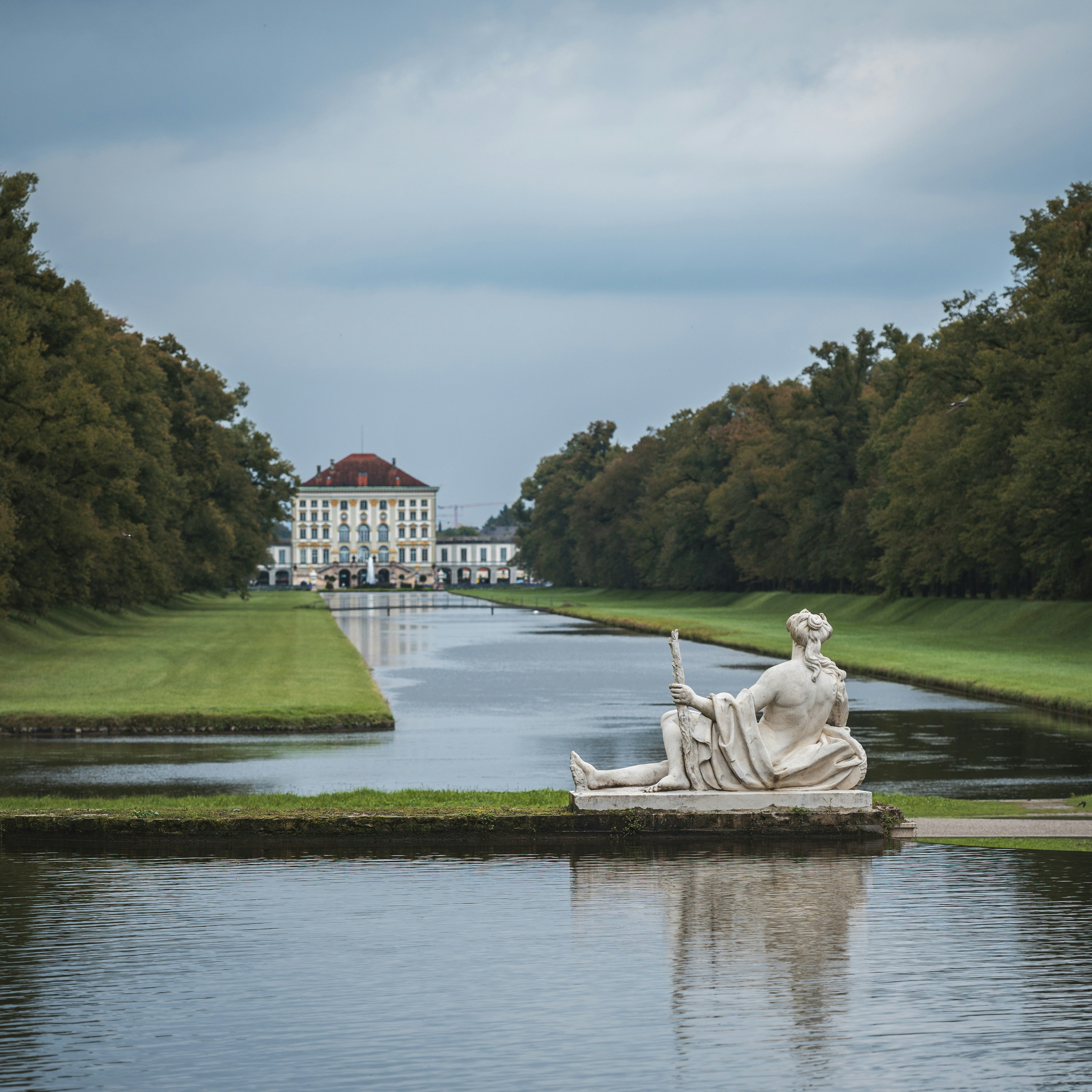 A large white statue sitting on top of a lush green field