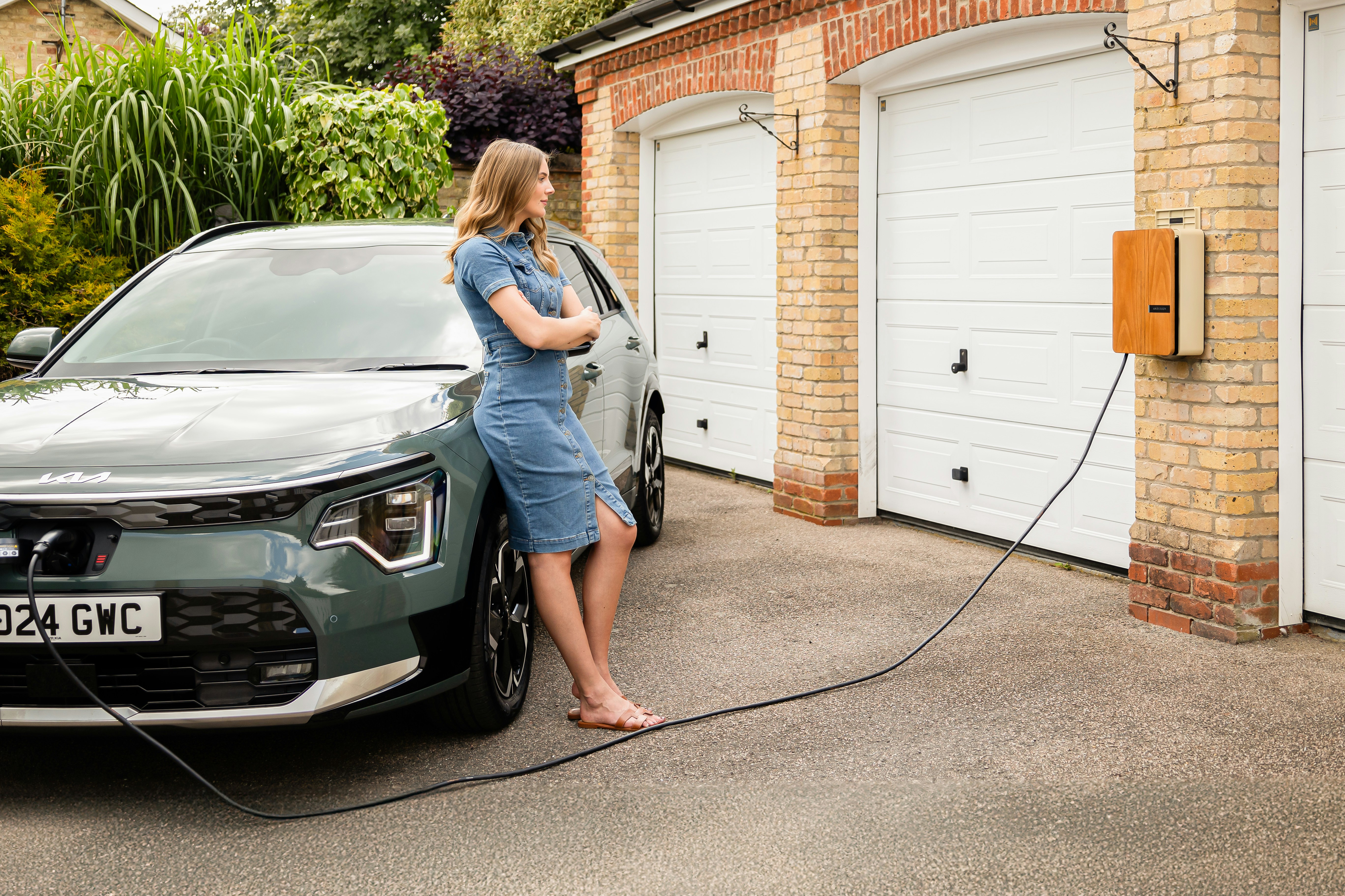 American family plugging an electric car into a home charger in their driveway