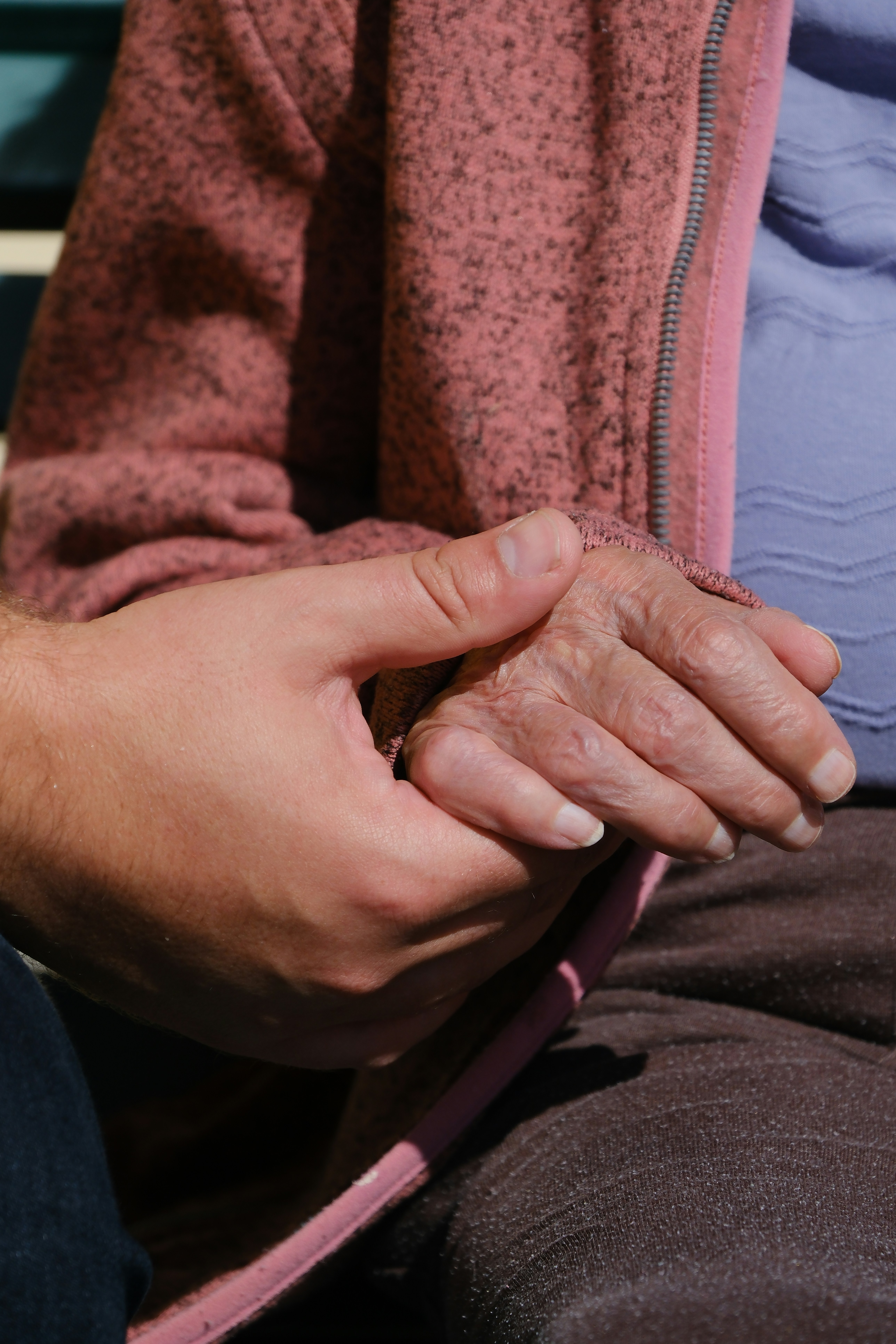 A person sitting on a bench holding their hands together
