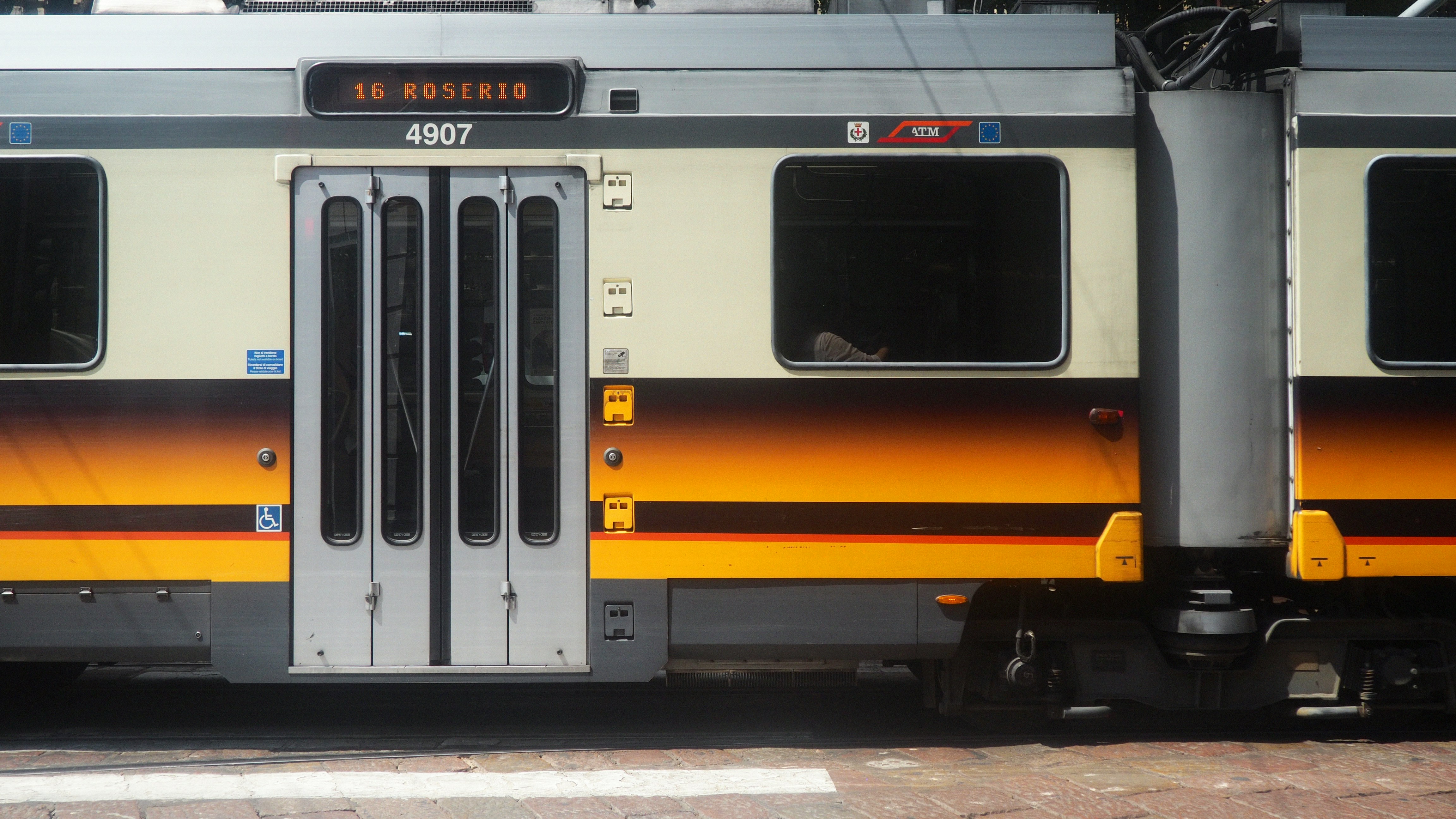 A yellow and gray train is on the tracks