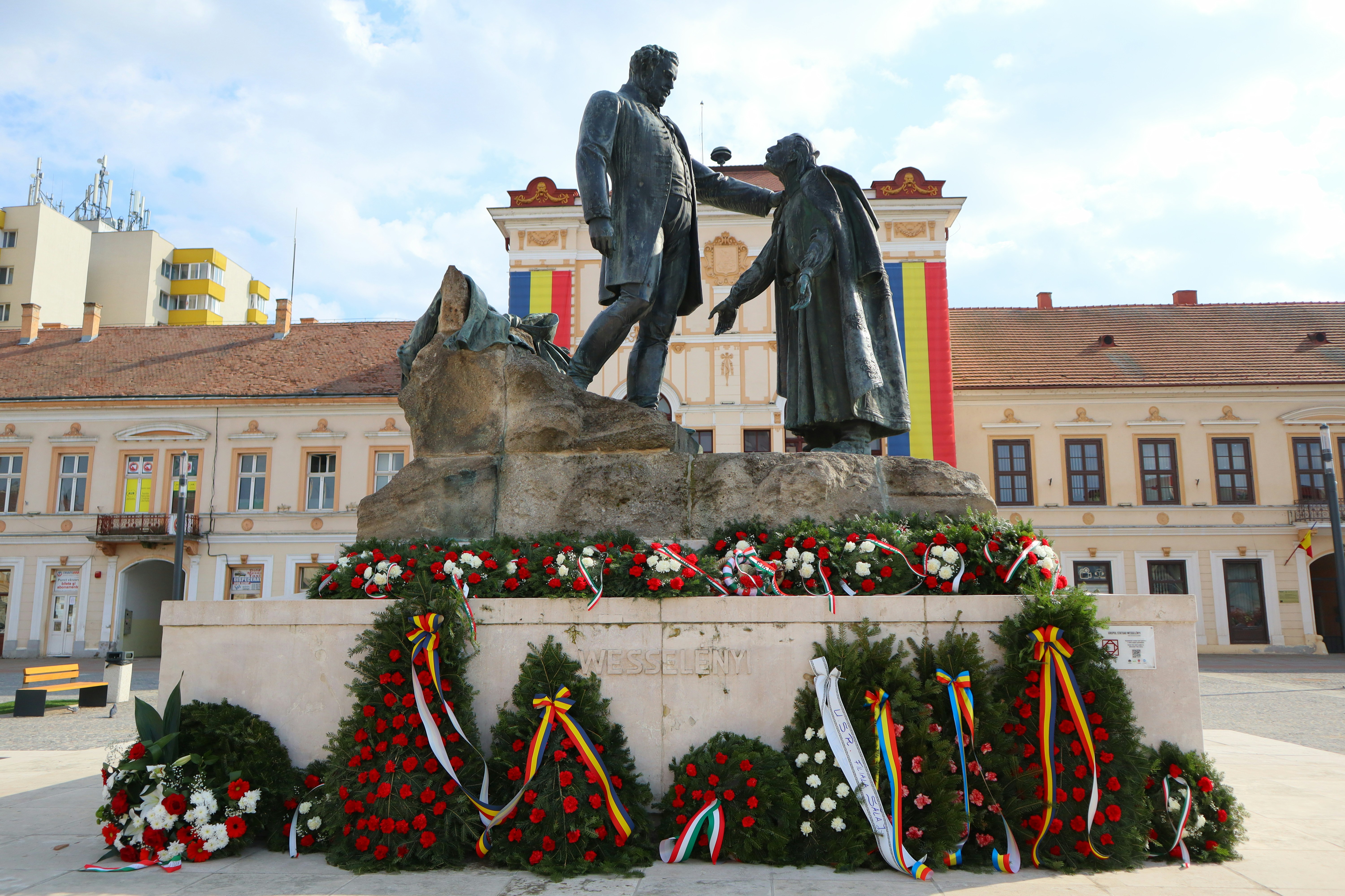 A statue of two men shaking hands in front of a building