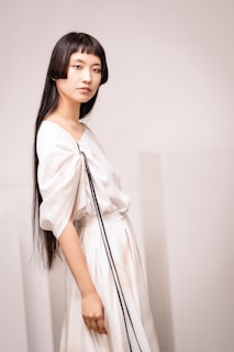 A woman in a white dress holding a black purse
