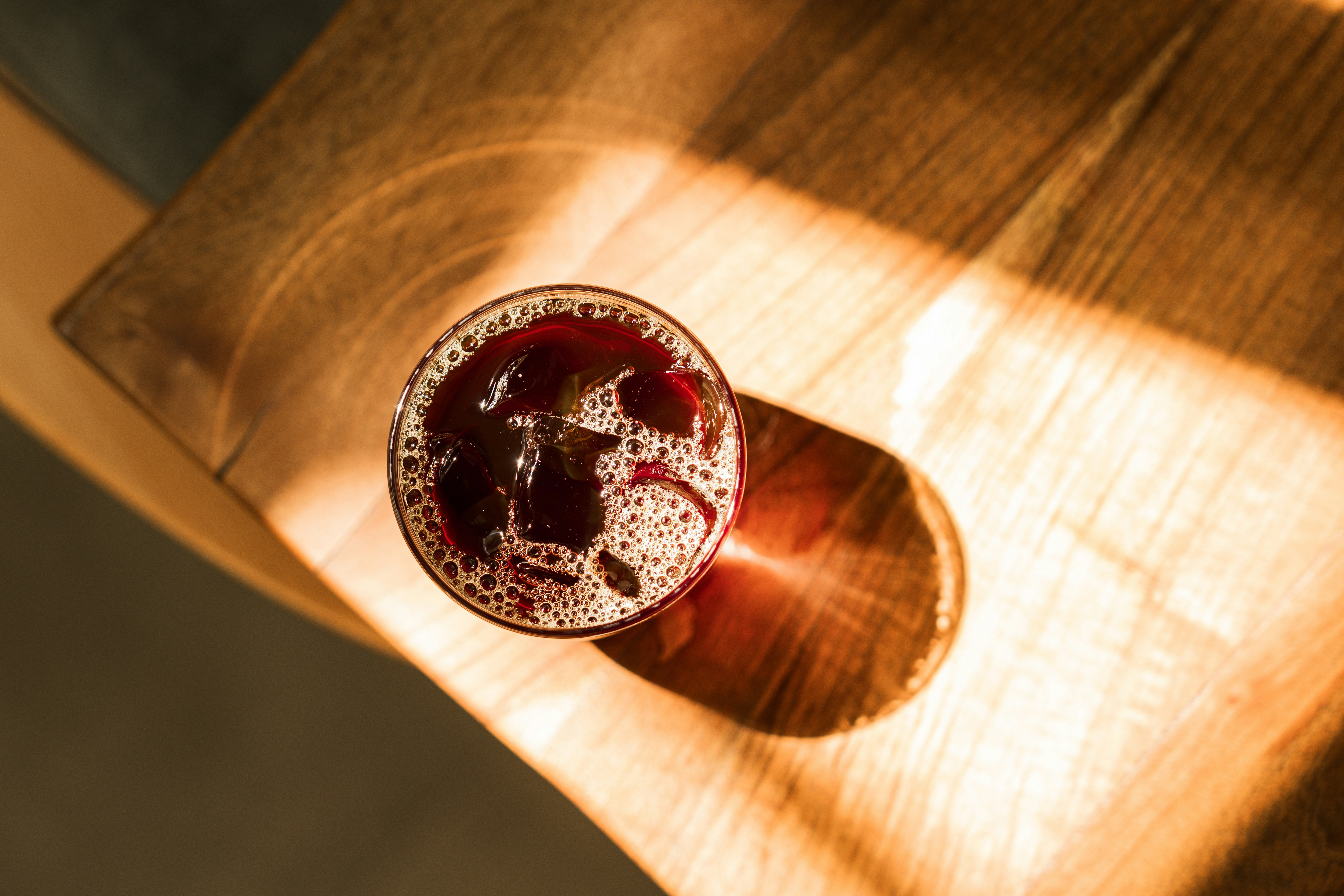 Glass of beer in sunlight on a wooden table