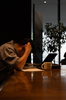 A man sitting at a table with his head in his hands