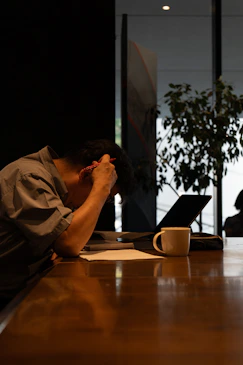 A man sitting at a table with his head in his hands