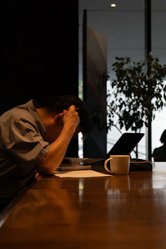 A man sitting at a table with his head in his hands