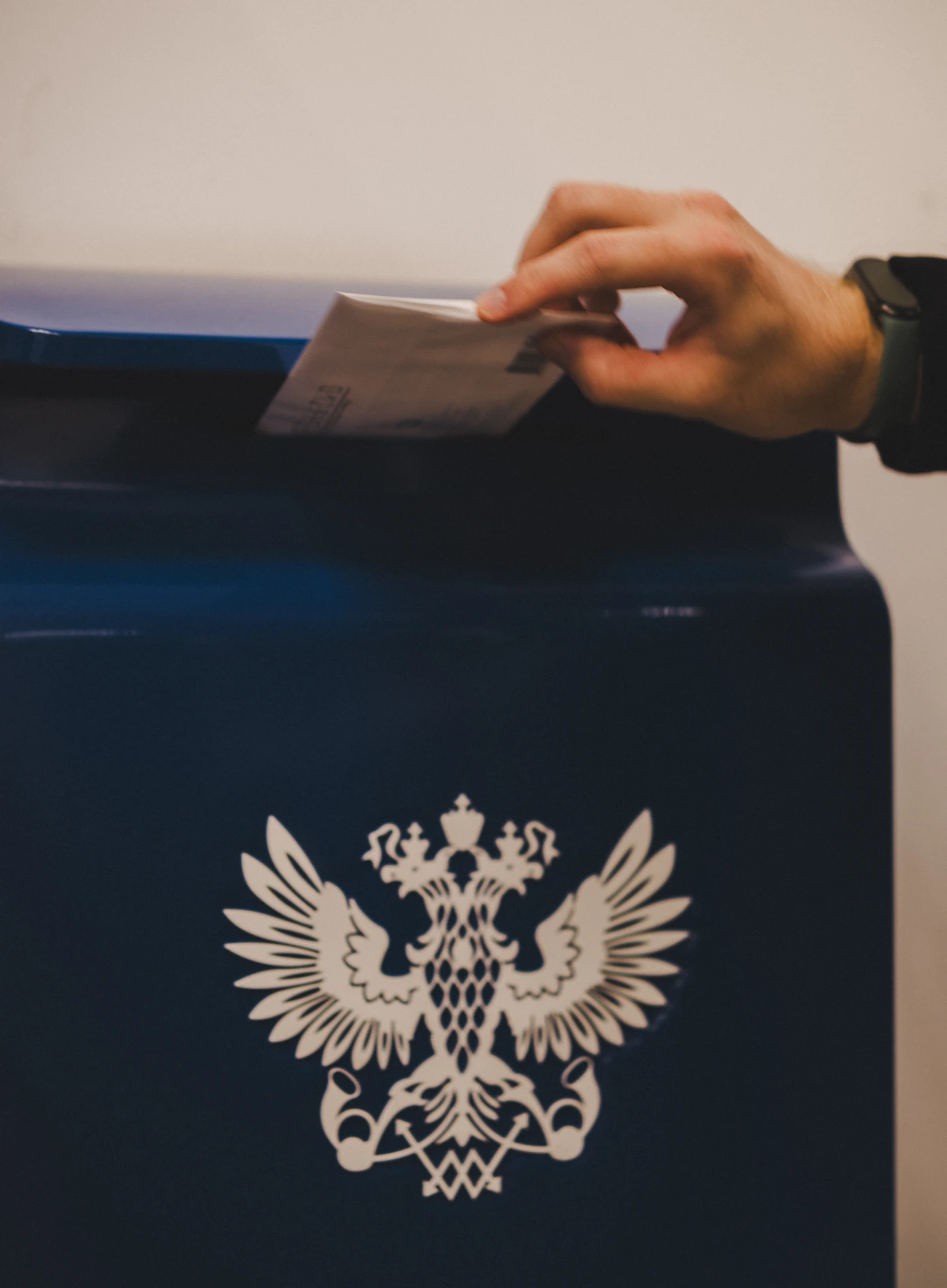A hand placing a folded ballot into a voting box, analogous to how an identical vote produced very different agent behavior depending on whether the office actually carried authority over something scarce