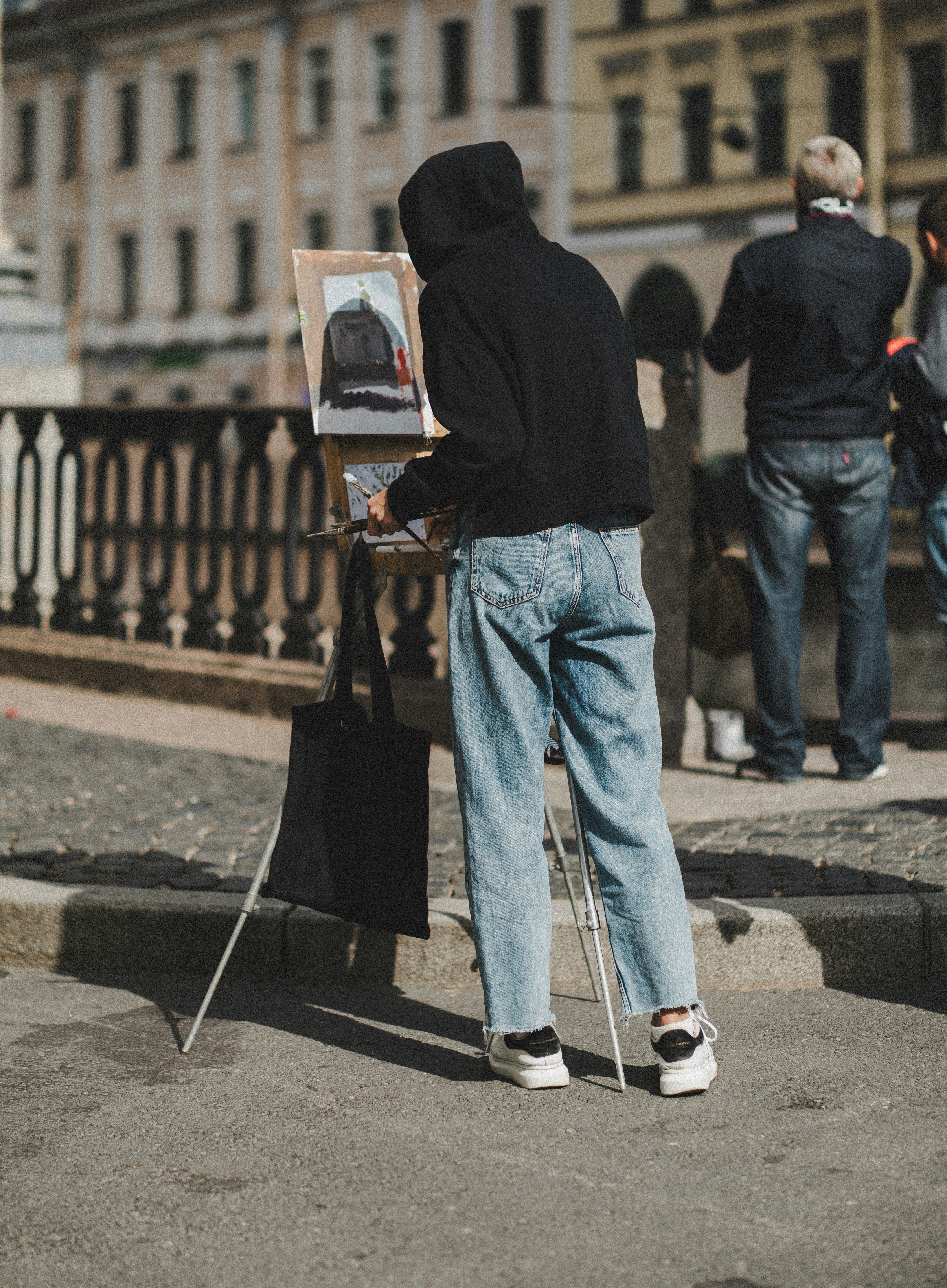 A man standing next to a painting on a easel