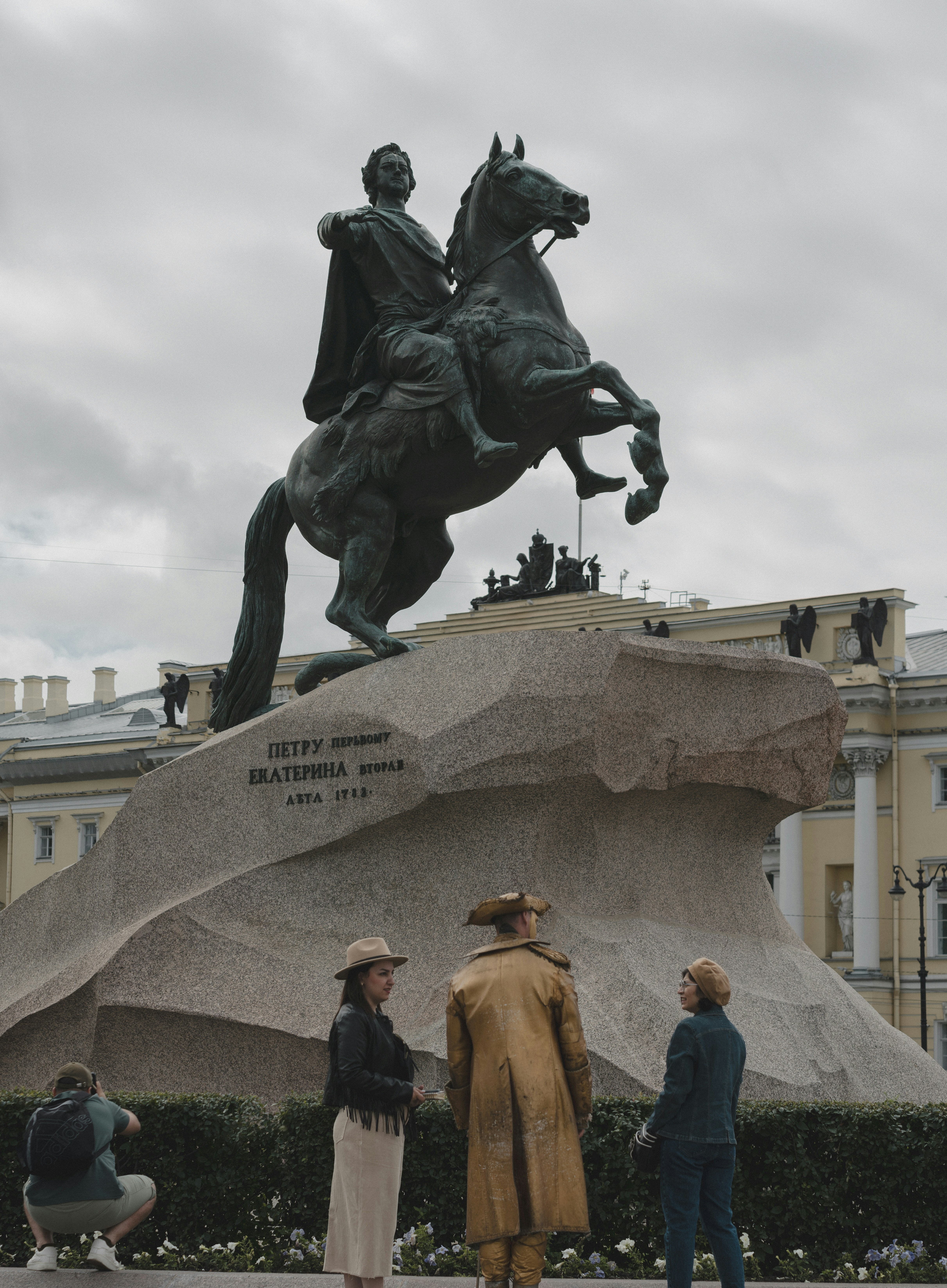 A group of people standing around a statue of a man on a horse