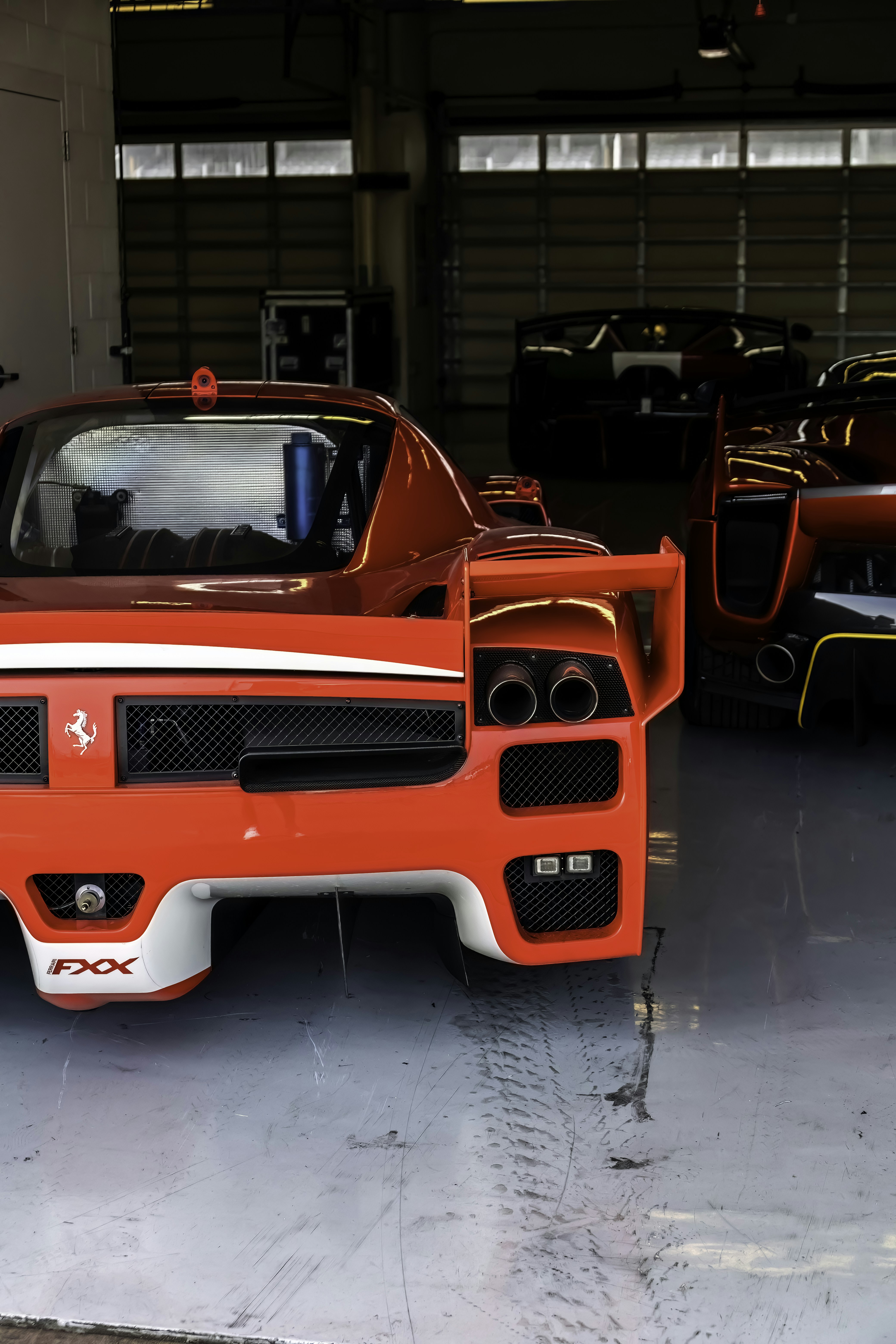 Um carro vermelho estacionado em uma garagem ao lado de outros carros