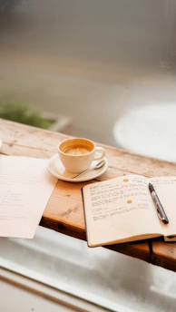 A cup of coffee and a notebook on a wooden table