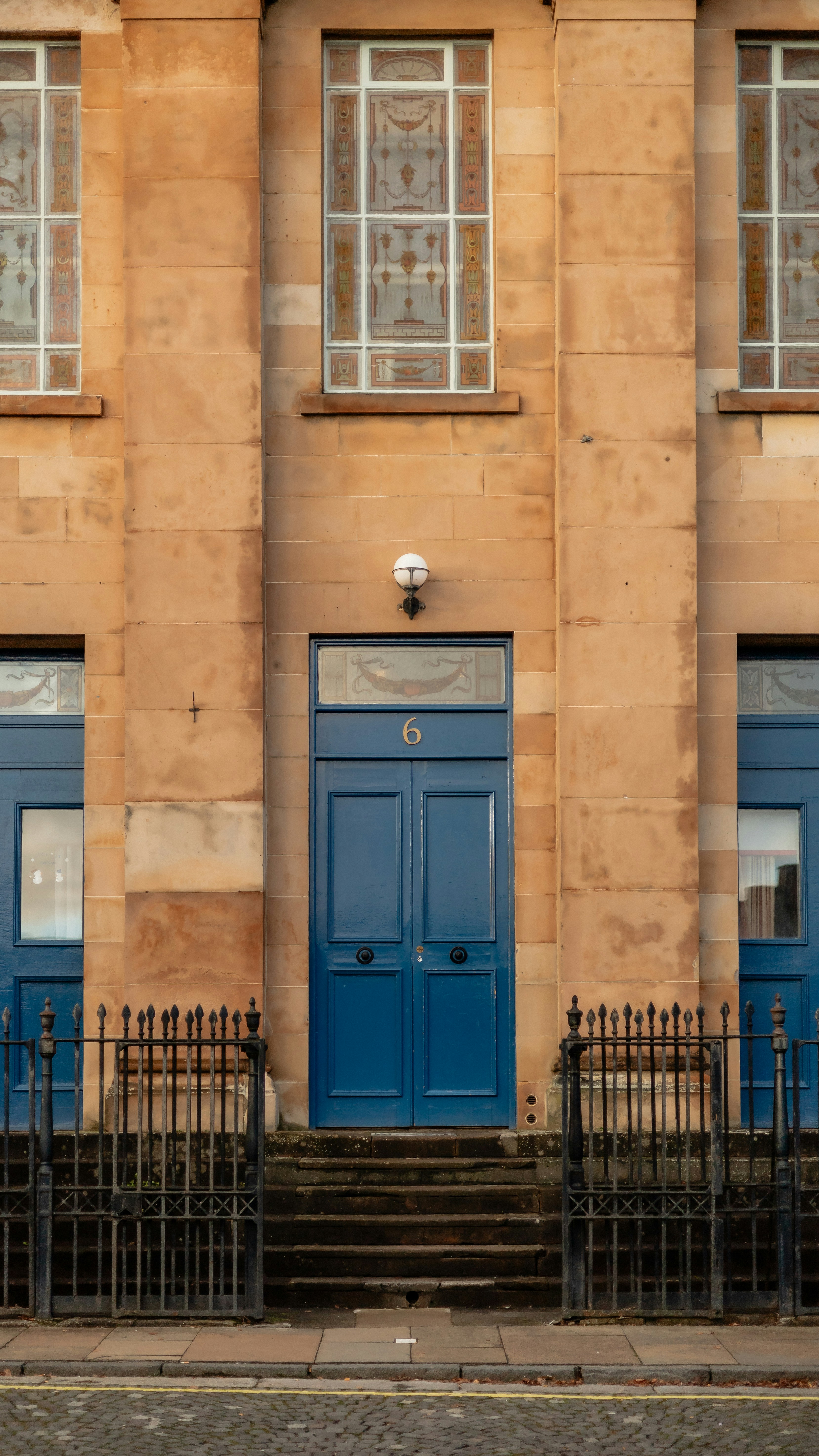 A building with two blue doors and a black fence