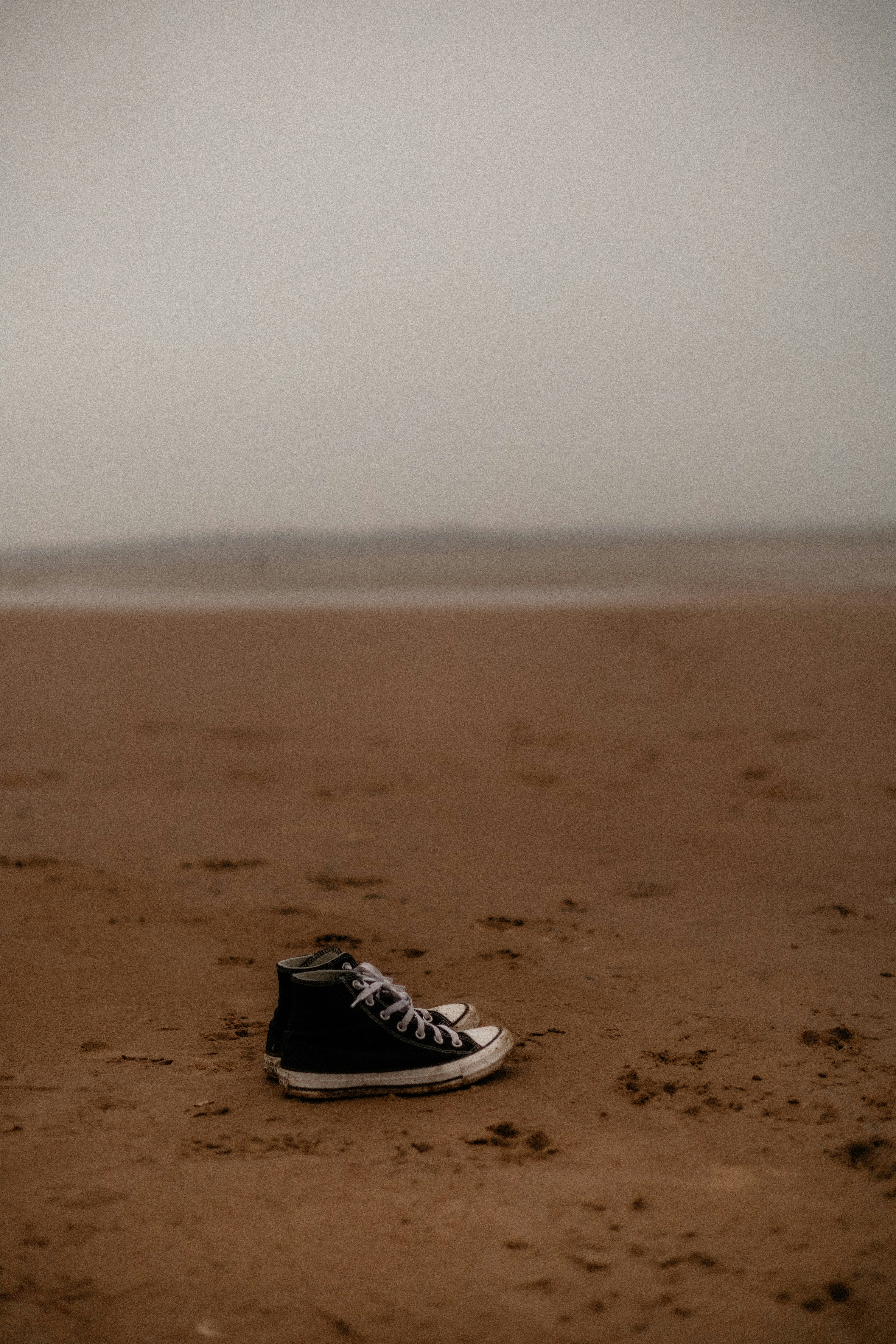 A pair of black shoes sitting on top of a sandy beach