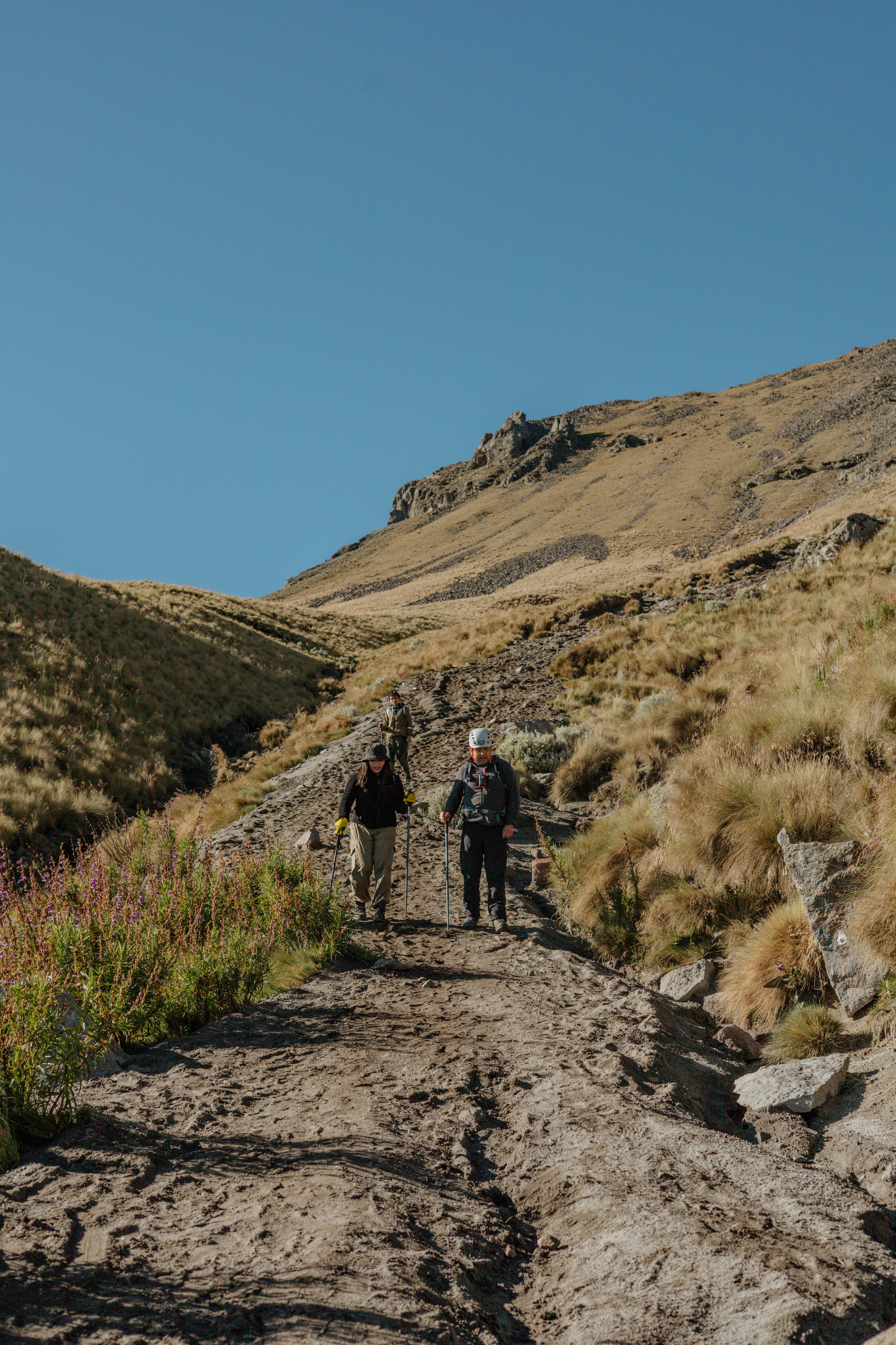 A couple of people walking down a dirt road