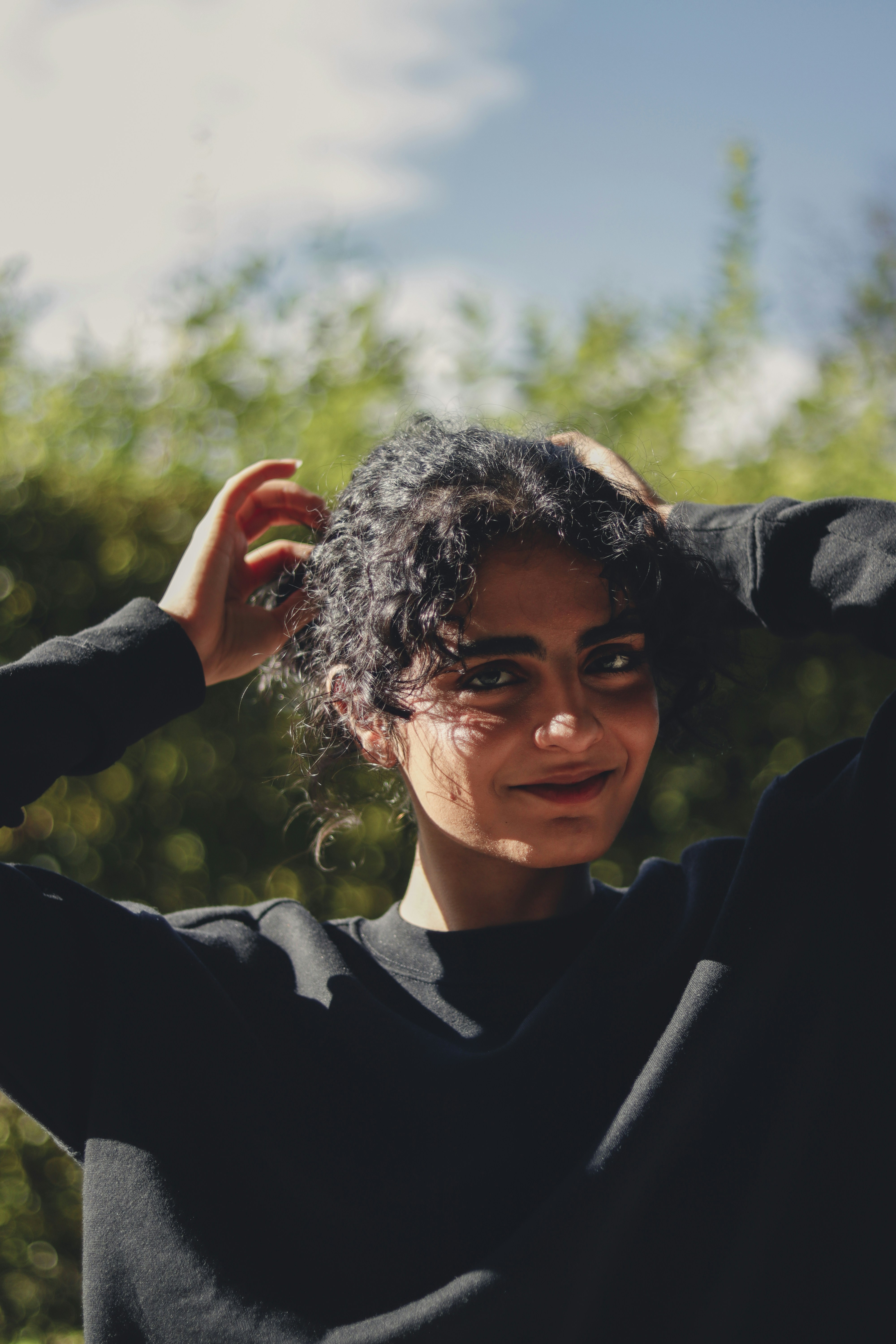 A woman in a black shirt is holding her hair
