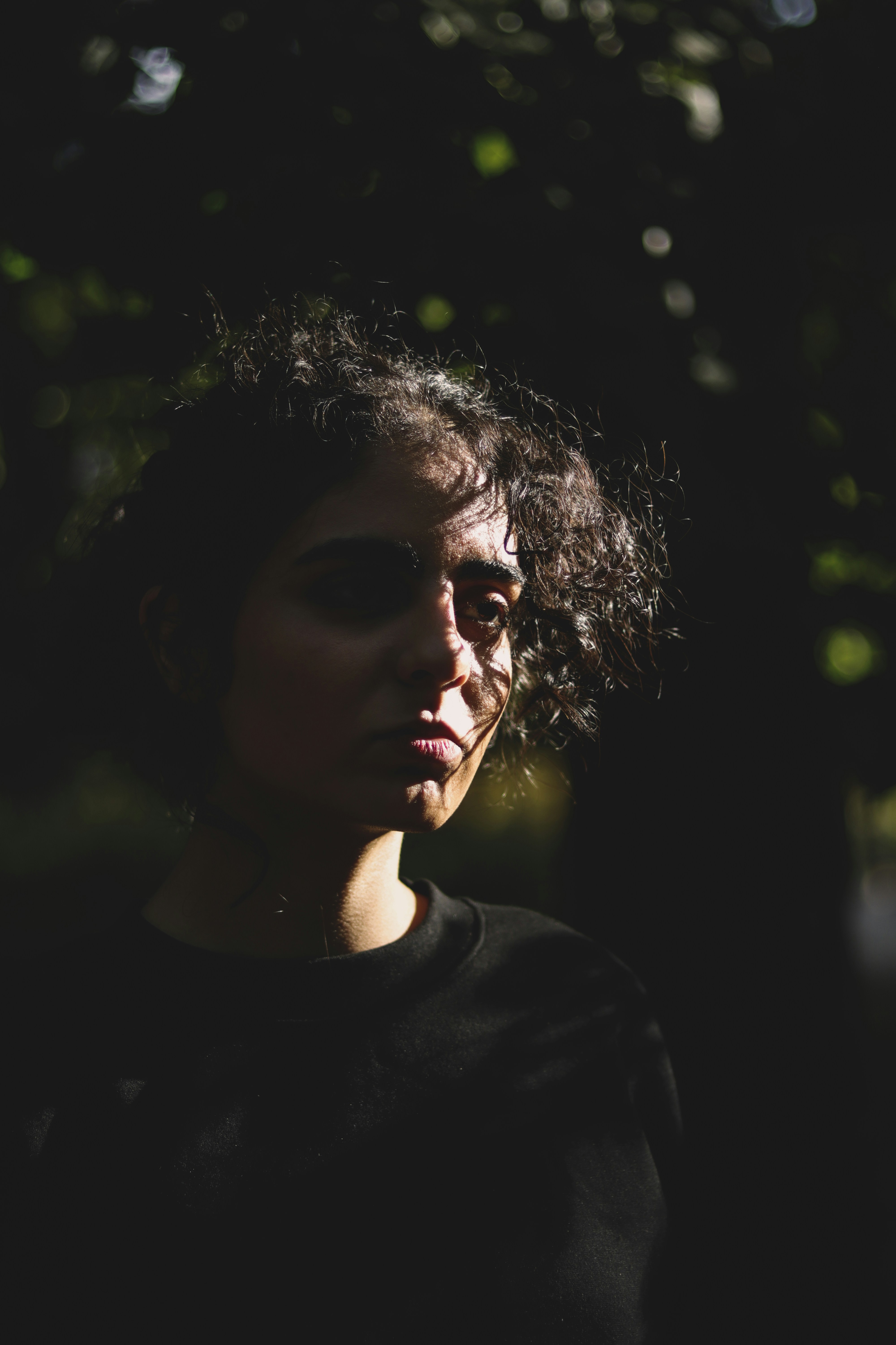 A woman standing in the dark with her eyes closed