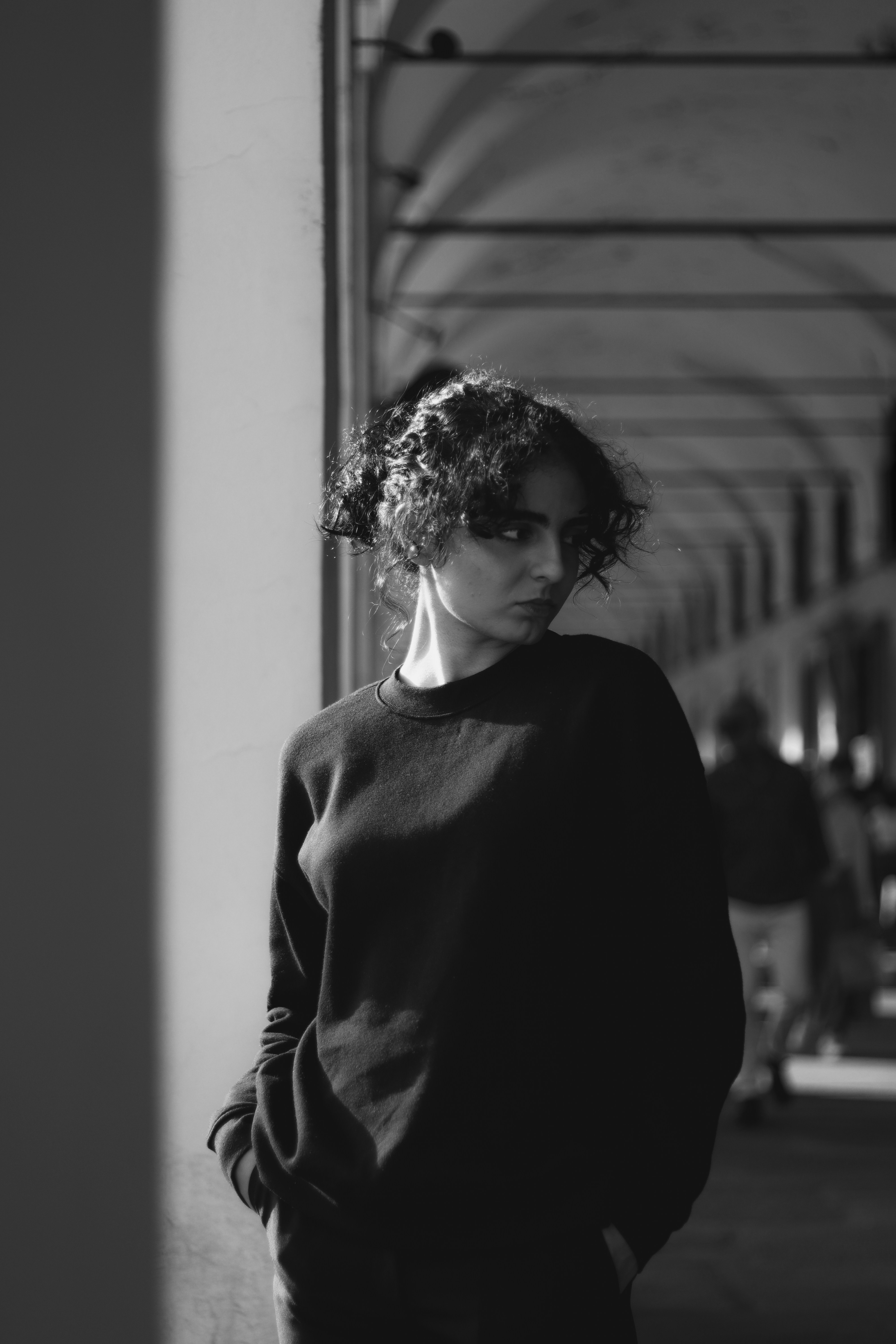 A black and white photo of a woman leaning against a wall