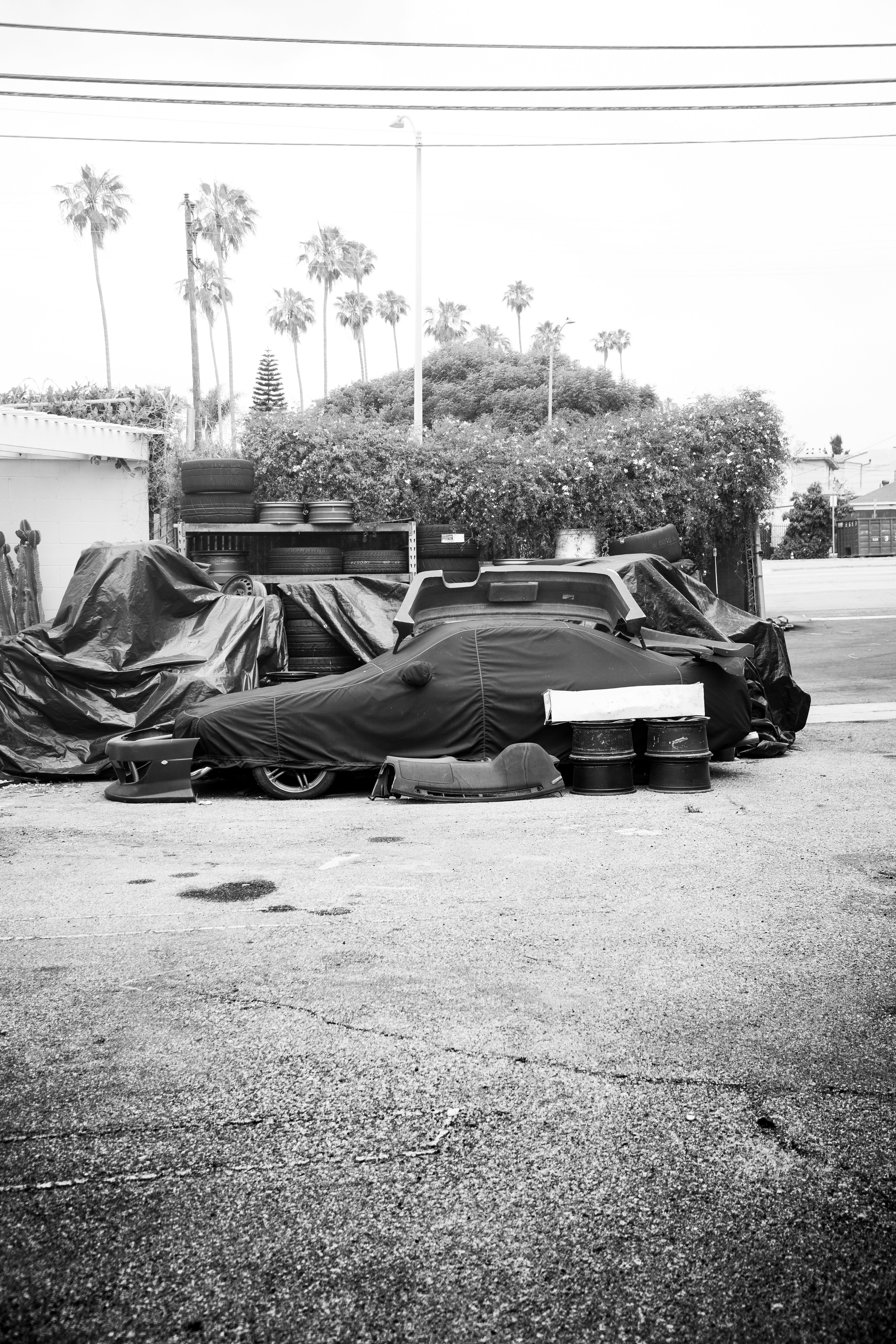 A black and white photo of a car covered in tarp